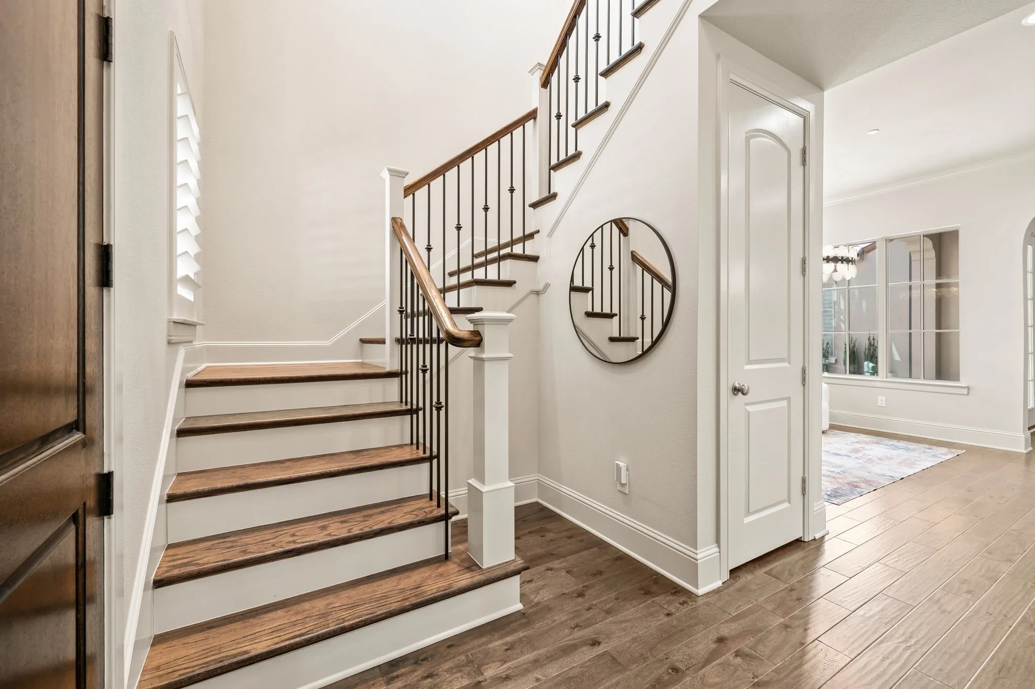 Hardwood flooring and staircase with wood treads, white risers, and wrought iron balusters