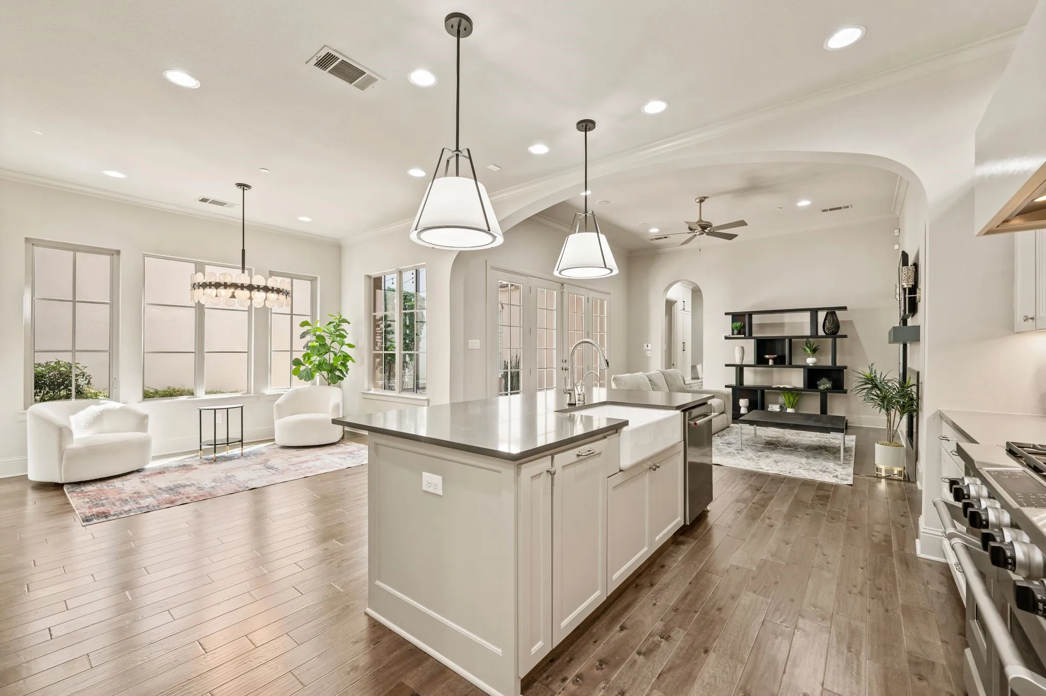 Open-concept kitchen and living area featuring wood-finish flooring, recessed lighting, a kitchen island with pendant lights, and arched doorways