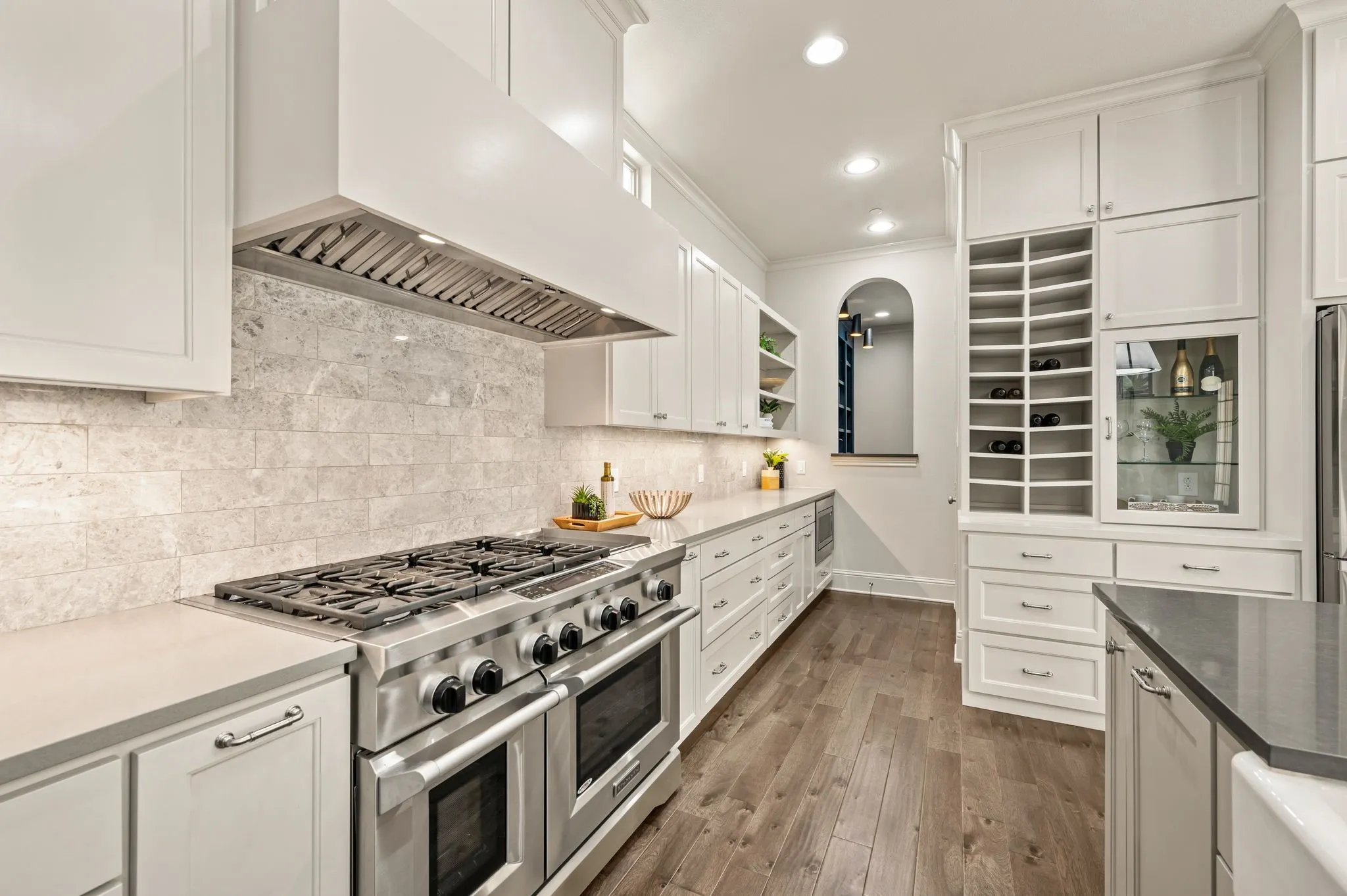 Gourmet kitchen with stainless steel range, custom range hood, and light-toned backsplash