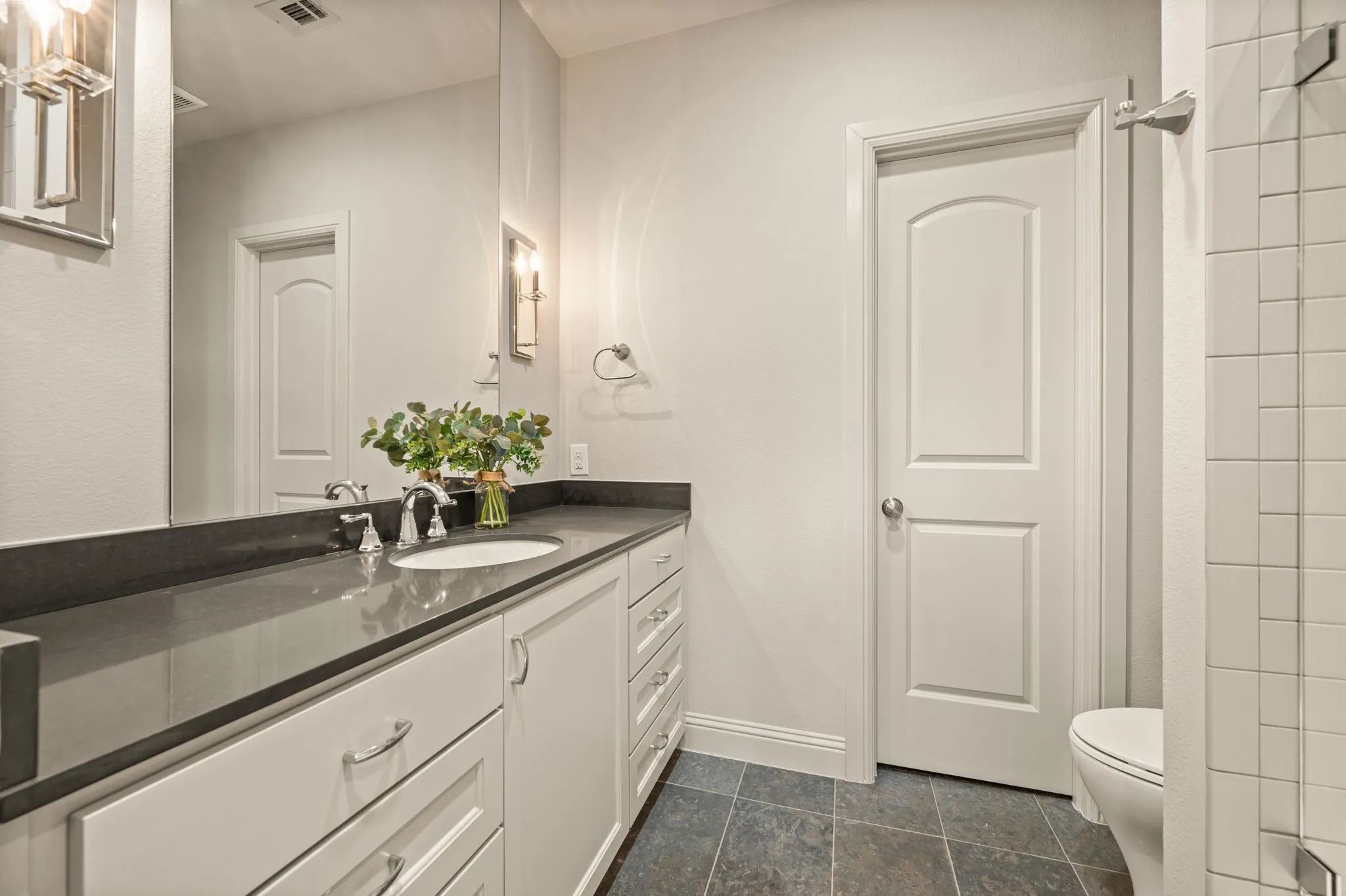 Spacious vanity with a dark countertop, undermount sink, and polished chrome fixtures