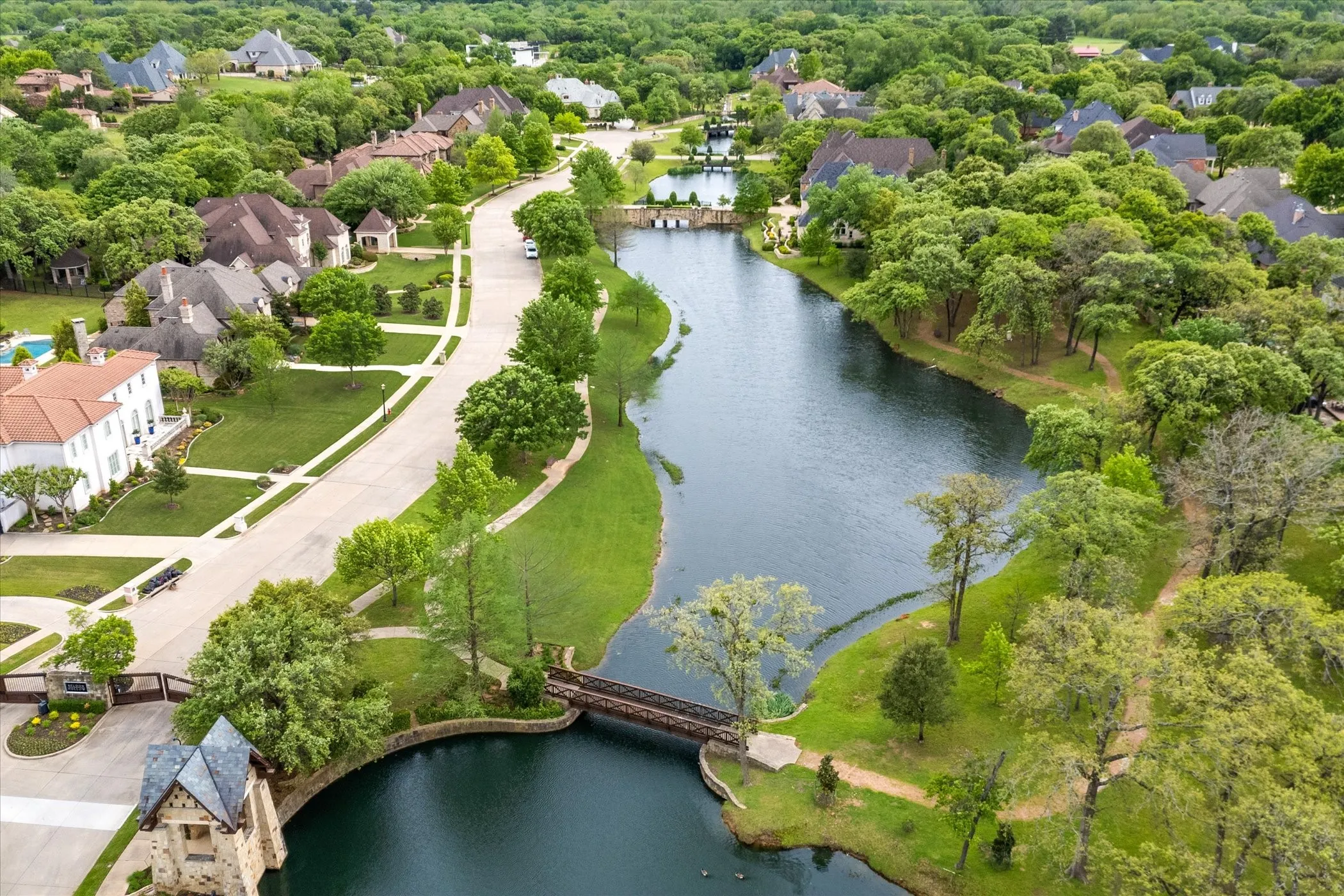 Aerial overview showcasing a community with extensive green space, a central waterway, and mature trees