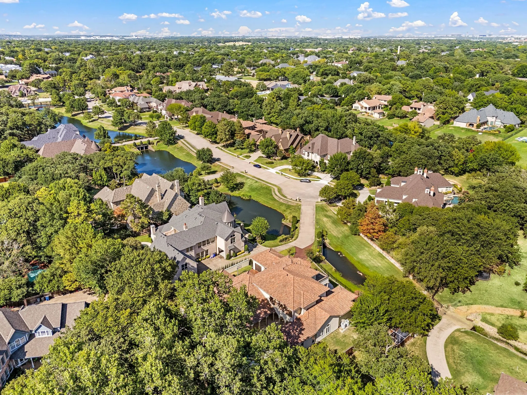 Lush tree-lined residential area with multiple water features, curvilinear streets, and varied architectural styles