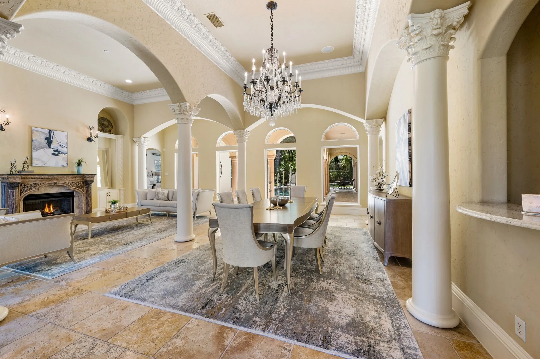 Elegant formal dining and living spaces showcase soaring ceilings with crown molding, round columns with classical capitals, and a crystal chandelier
