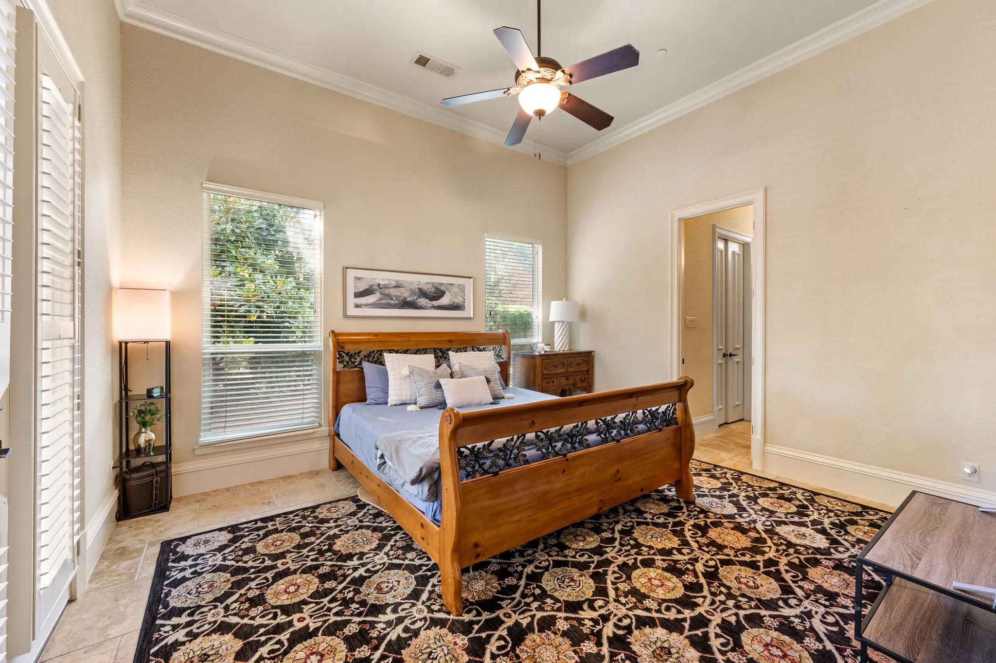 Recessed ceiling with crown molding, dual windows with blinds, ceiling fan, and tile flooring
