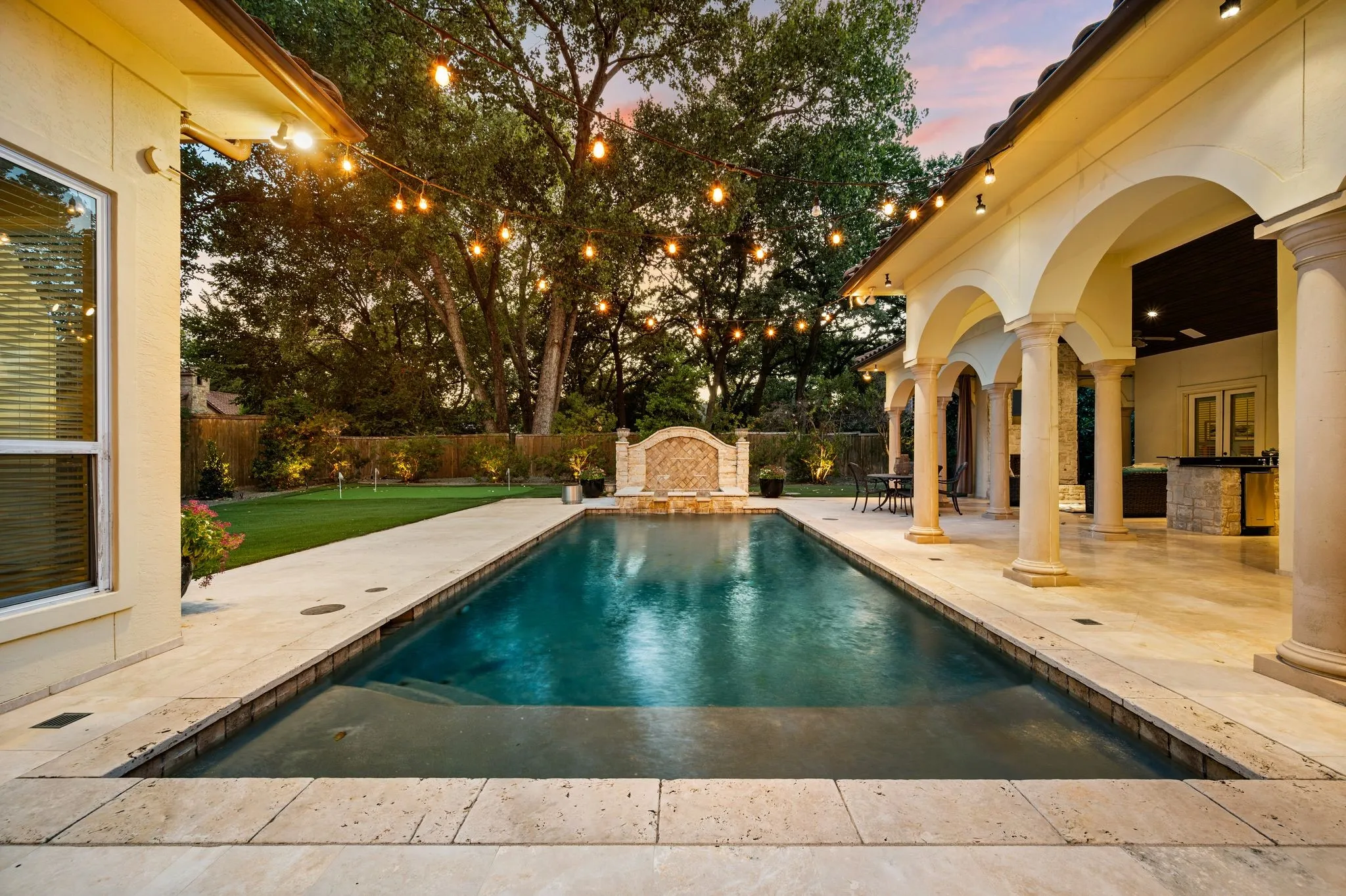 Rectangular swimming pool with integrated steps, surrounded by extensive light-toned stone paving