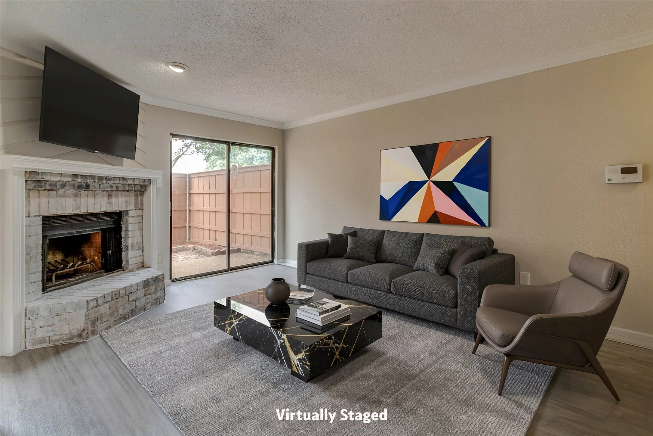 Brick fireplace with a painted mantel, wood-finish flooring, and sliding glass doors leading to a private outdoor space