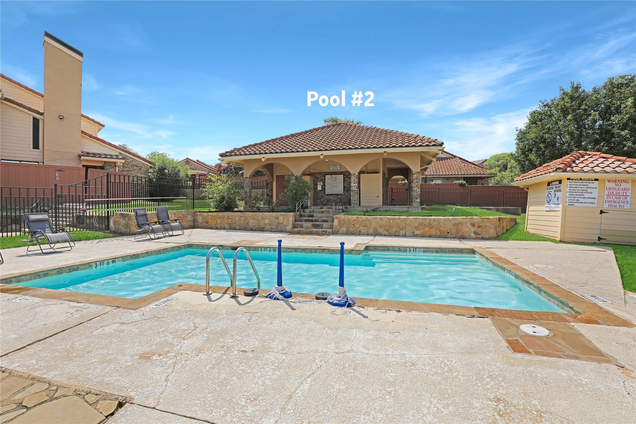 Rectangular swimming pool with integrated steps, surrounded by a concrete deck and a stone-clad retaining wall