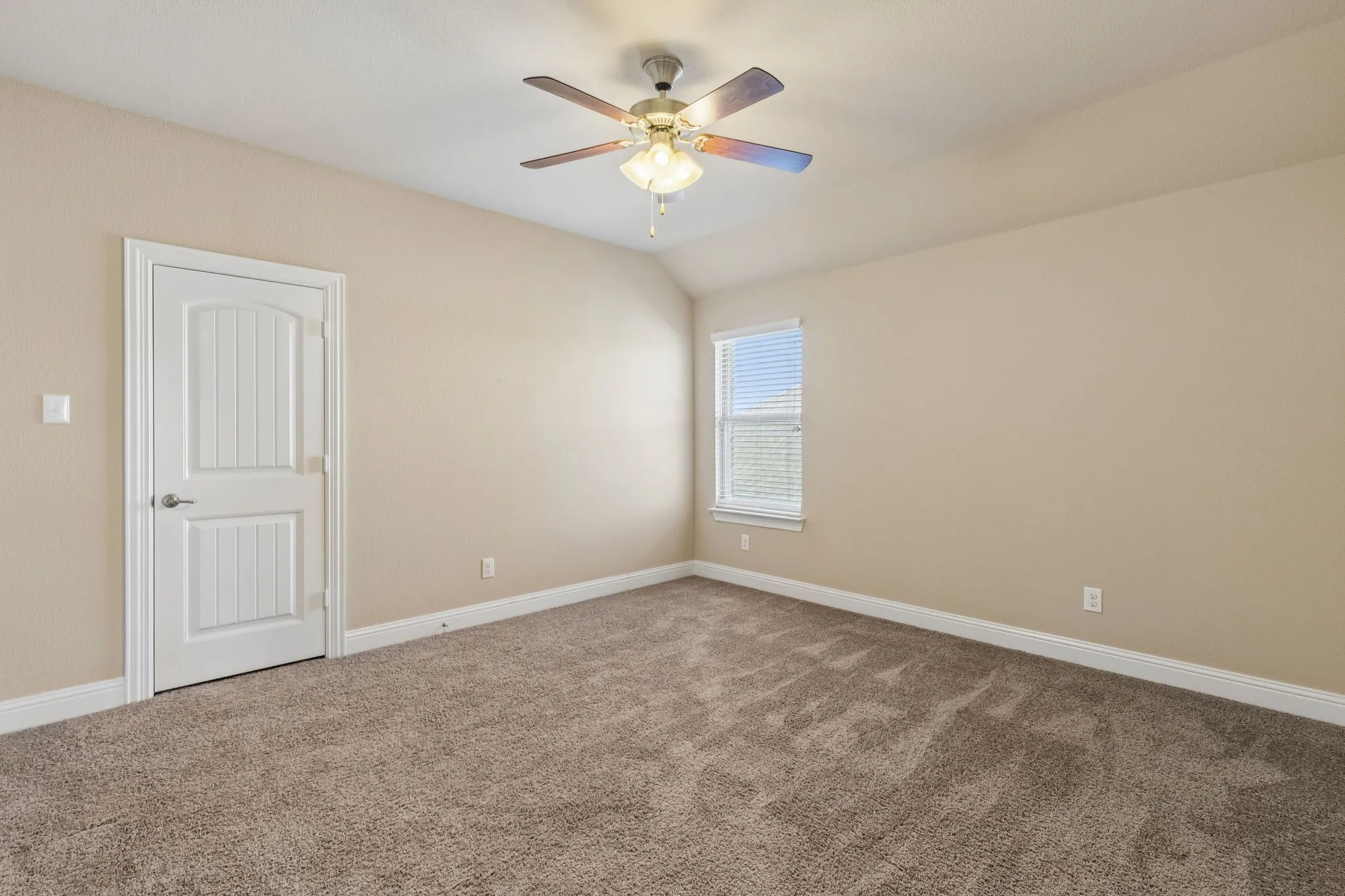 Vaulted ceiling, carpet flooring, ceiling fan with integrated lighting, white trim, and a paneled interior door