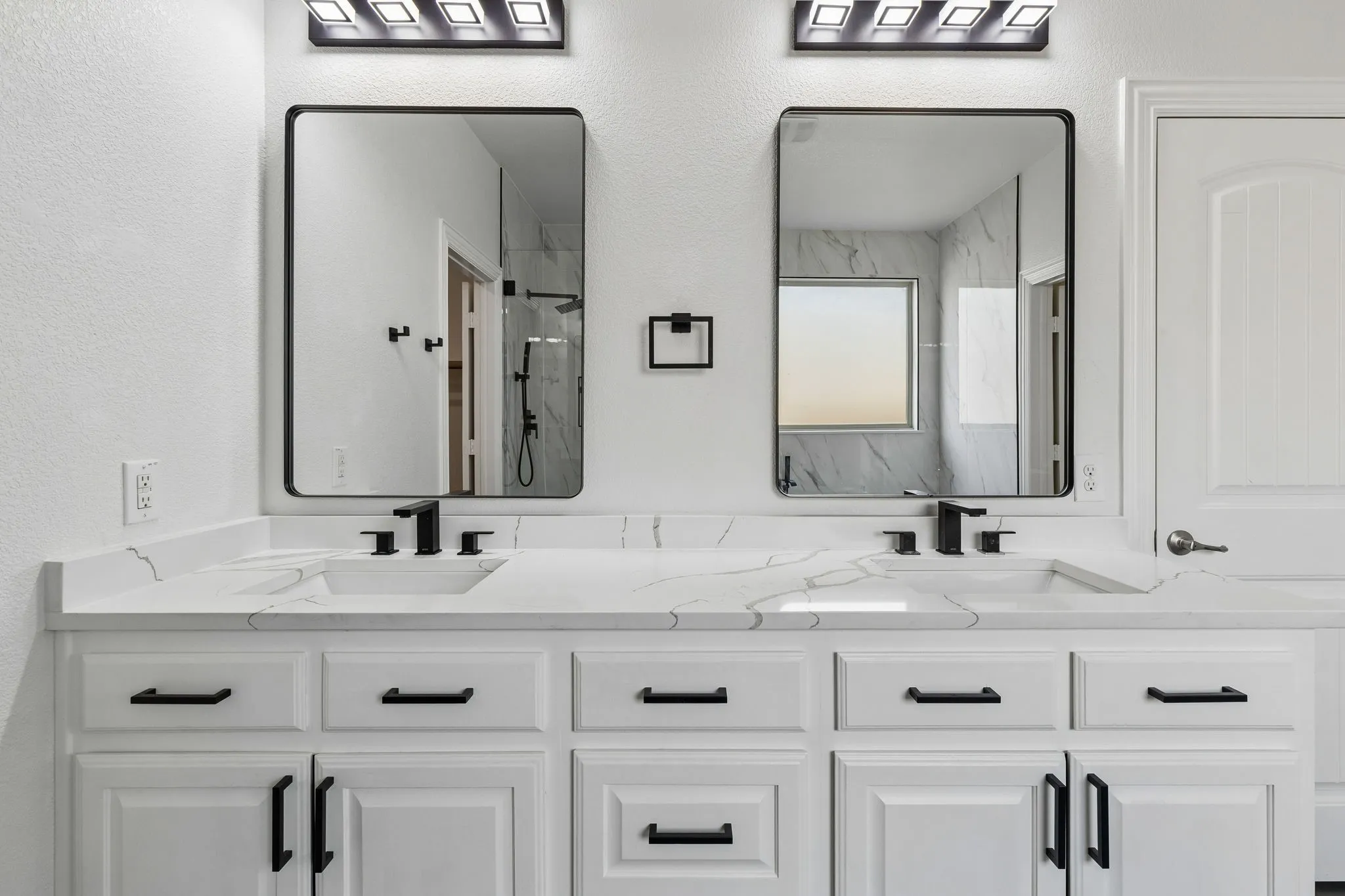 Dual vanity with integrated sinks, black fixtures, white cabinetry, and rectangular mirrors