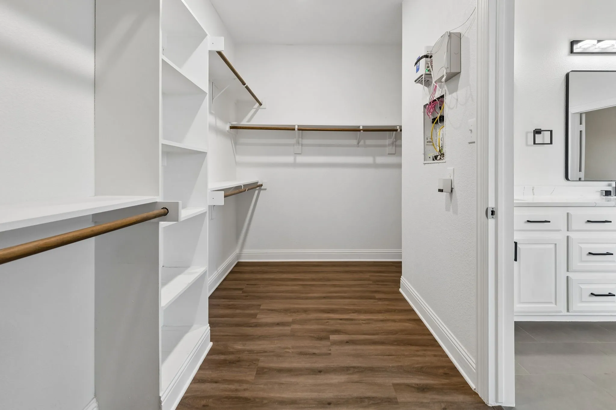 Walk-in closet featuring built-in shelving, hanging rods, and wood-finish flooring