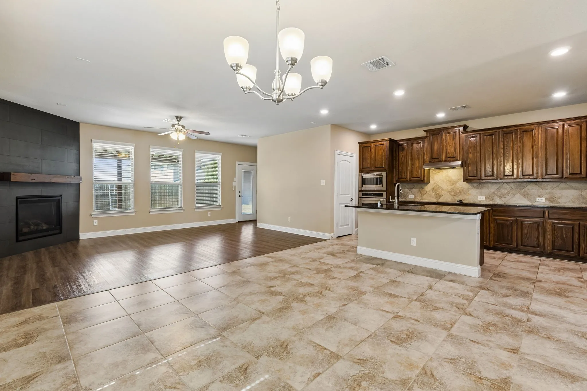 Open-concept living space with a kitchen island, dark wood cabinetry, a tiled backsplash, and recessed lighting