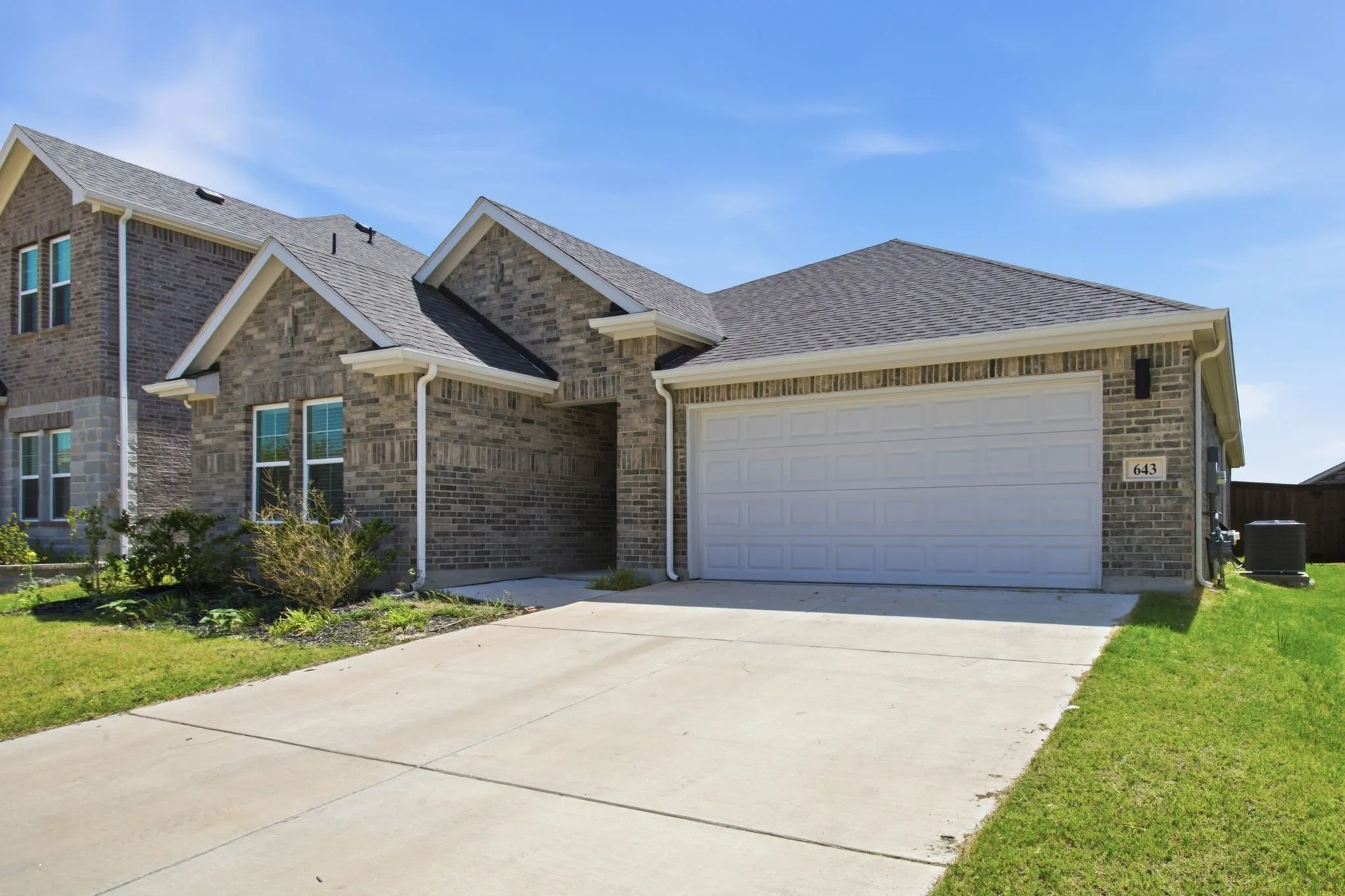 Brick exterior with a gabled roofline, concrete driveway, and attached garage