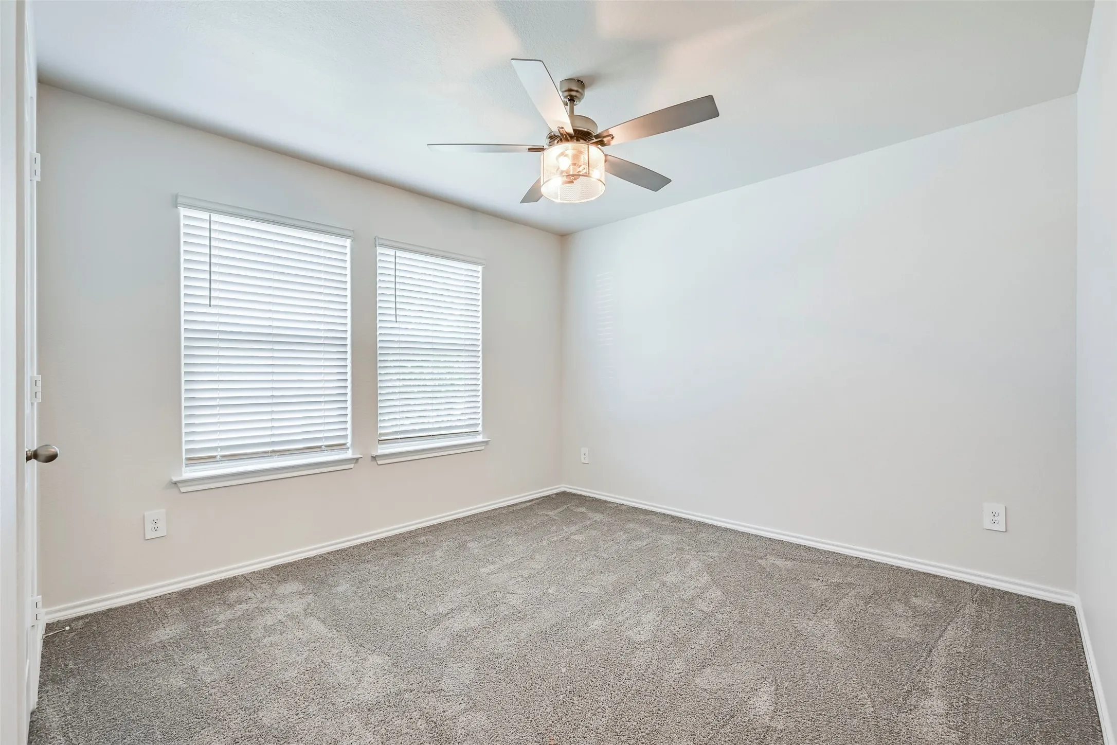 Recessed lighting, ceiling fan with integrated light, two windows with blinds, gray carpeting, and white walls