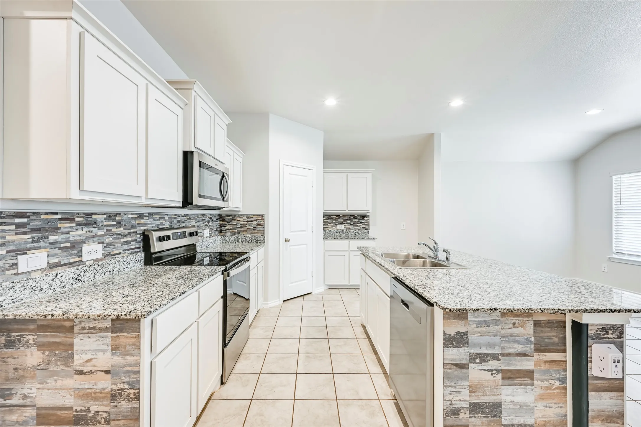Kitchen featuring white cabinetry, light-toned countertops, a mosaic tile backsplash, stainless steel appliances, and recessed lighting
