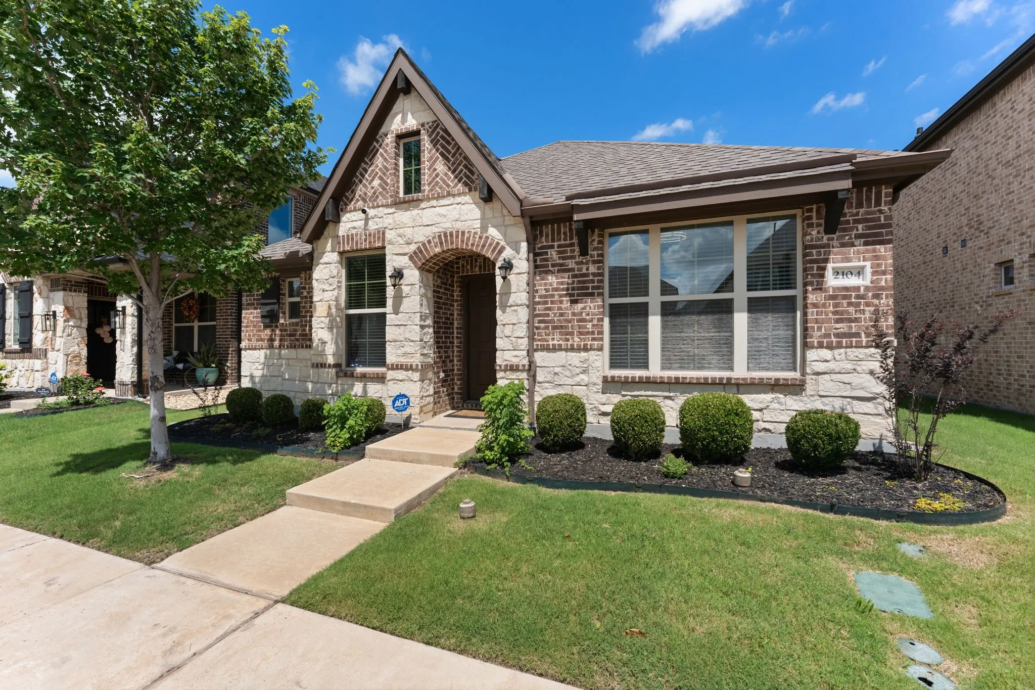 Brick and stone facade featuring an arched entry, prominent front-facing gable, and an integrated window box