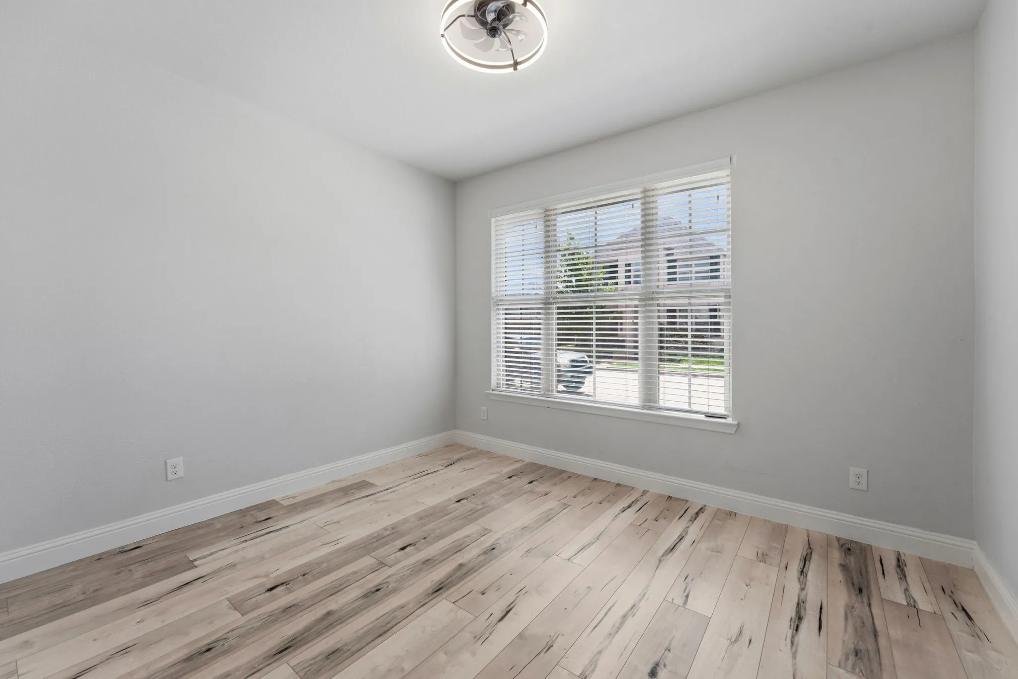 Bright interior space featuring wood-finish flooring, white baseboards, and neutral wall tones