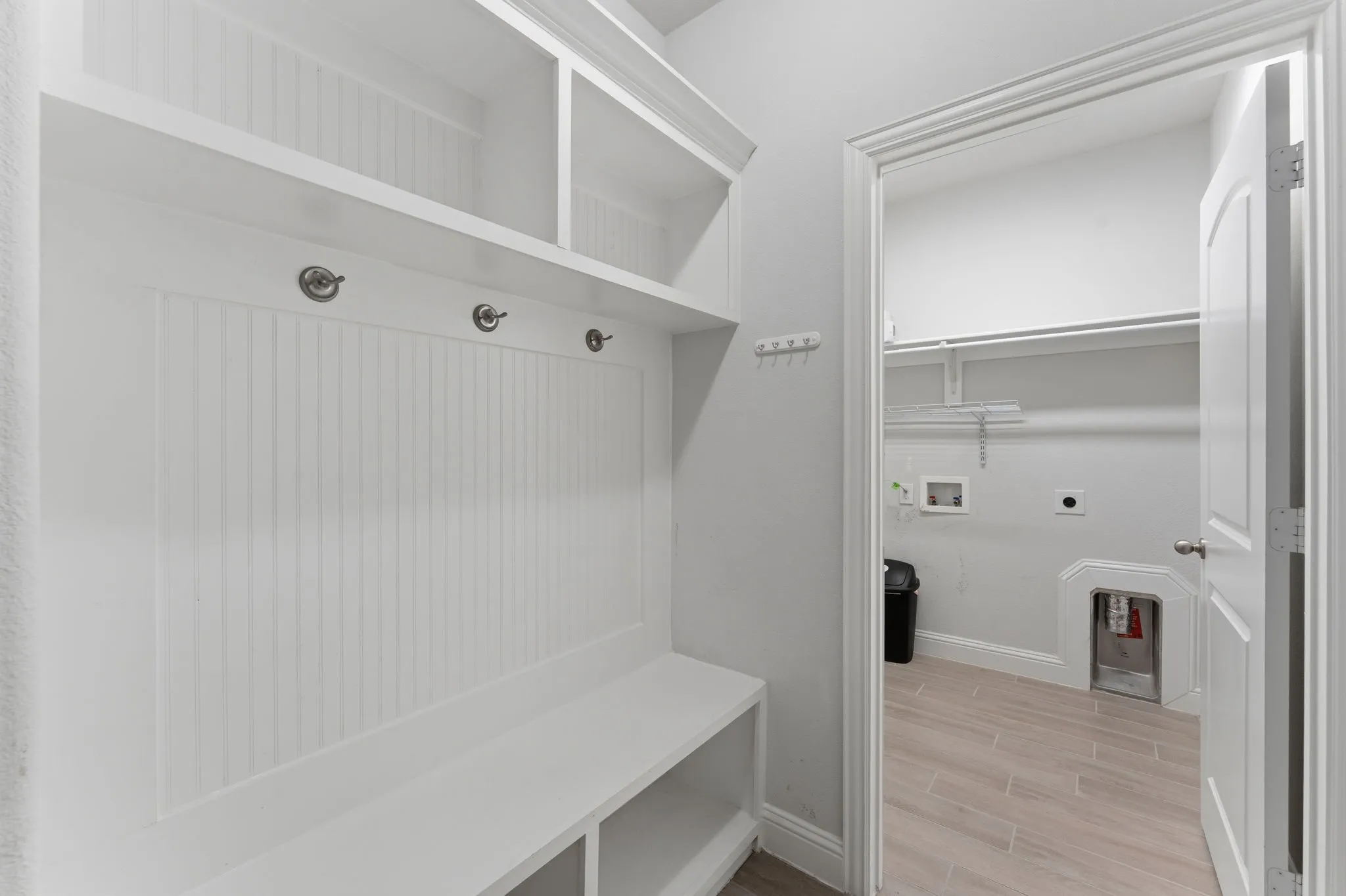 Built-in mudroom bench with beadboard backing, overhead shelving, and coat hooks