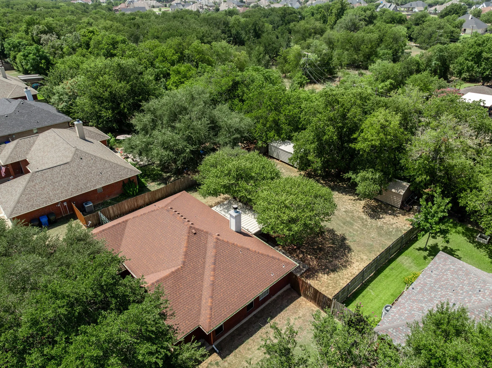 Expansive lot with mature trees, privacy fencing, and two outbuildings