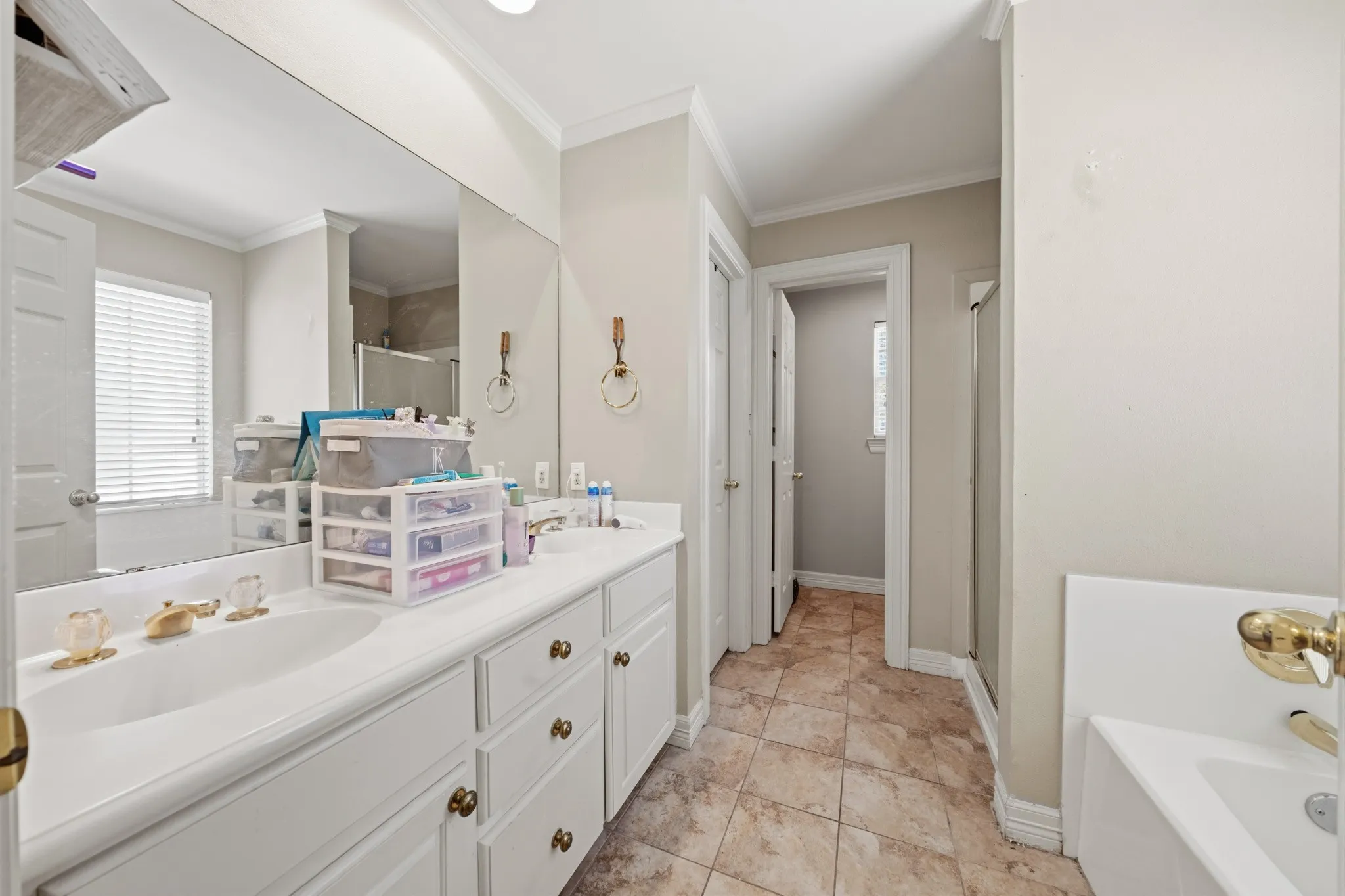 Dual vanity with white cabinetry, full-width mirror, and a built-in bathtub