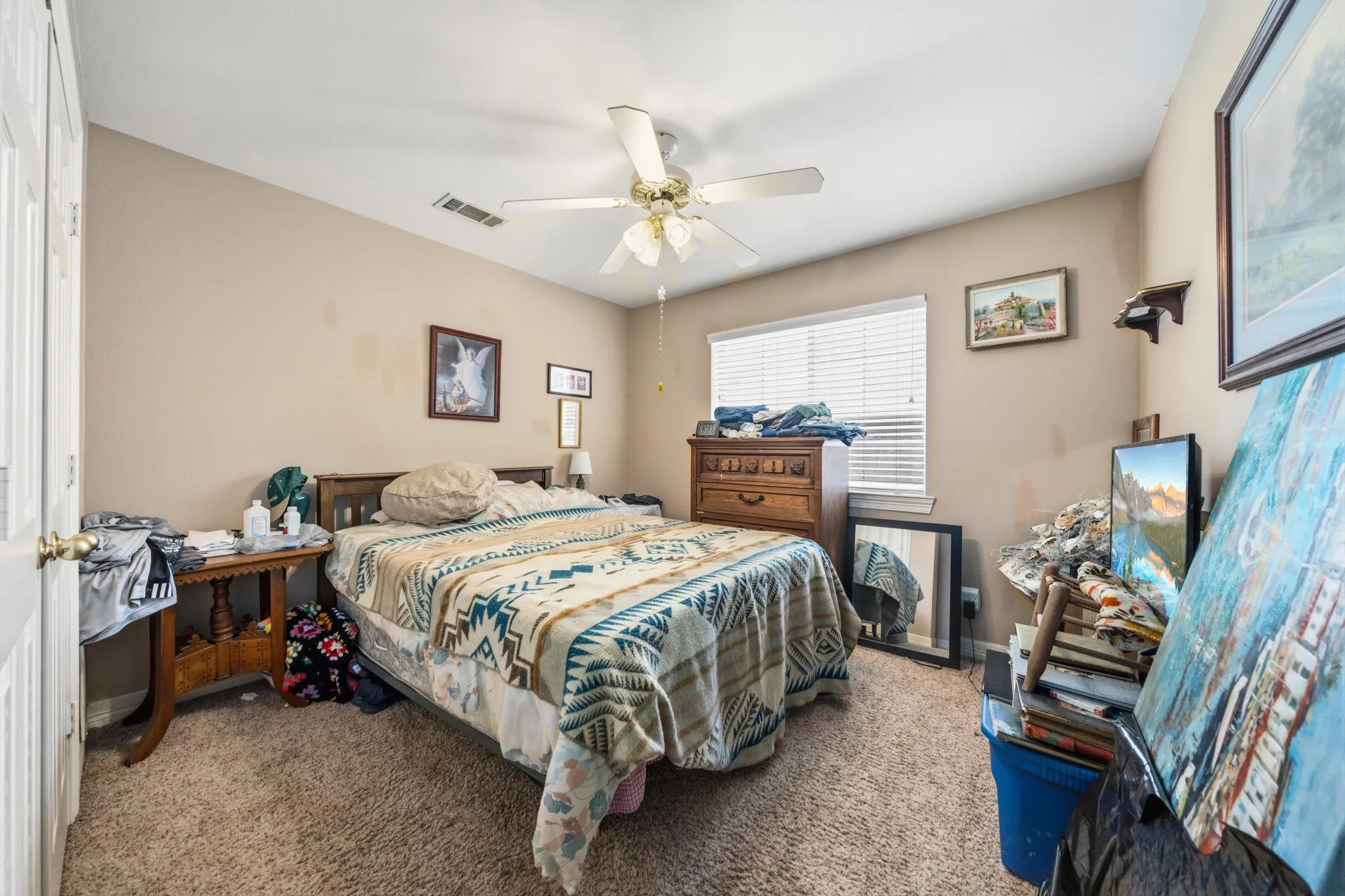 Spacious bedroom featuring carpeted flooring, ceiling fan with integrated lighting, and large window with plantation shutters providing natural light