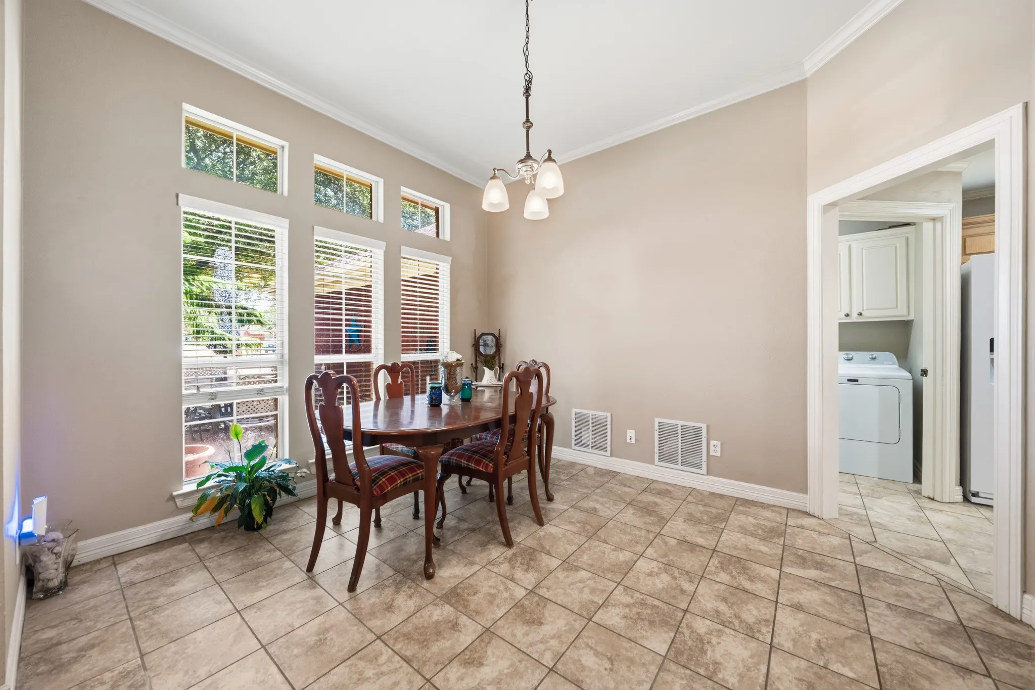 Vaulted ceiling with crown molding, tiled flooring, and a multi-pane window configuration with upper transom windows