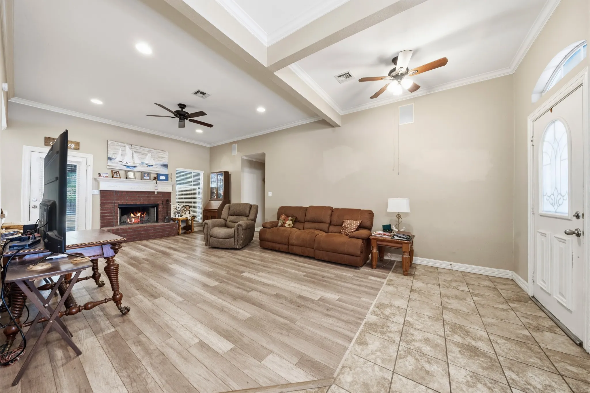 Spacious living area featuring wood-finish flooring, a brick fireplace with a mantel, recessed lighting, and ceiling fans