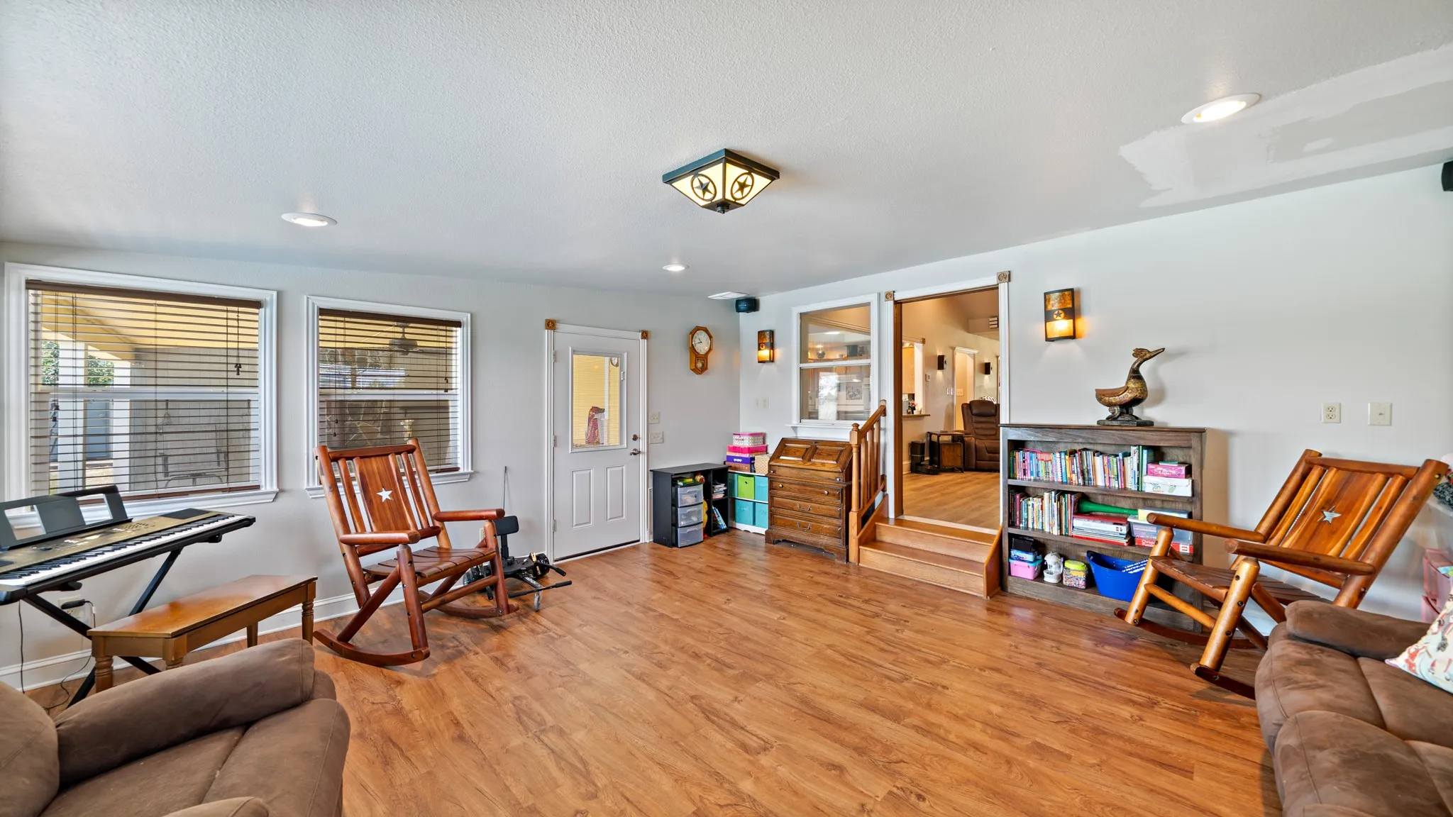 Spacious open-concept living area with wood-finish flooring, recessed ceiling lighting, and multiple windows providing natural light