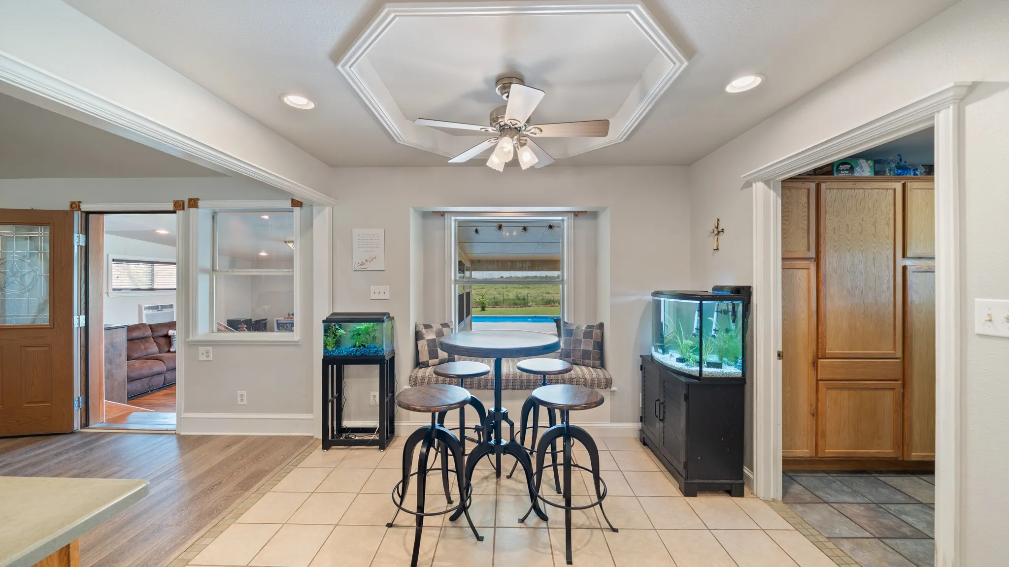 Bright, open recreation room featuring tile flooring, recessed ceiling lighting with ceiling fan, and multiple windows framing natural light
