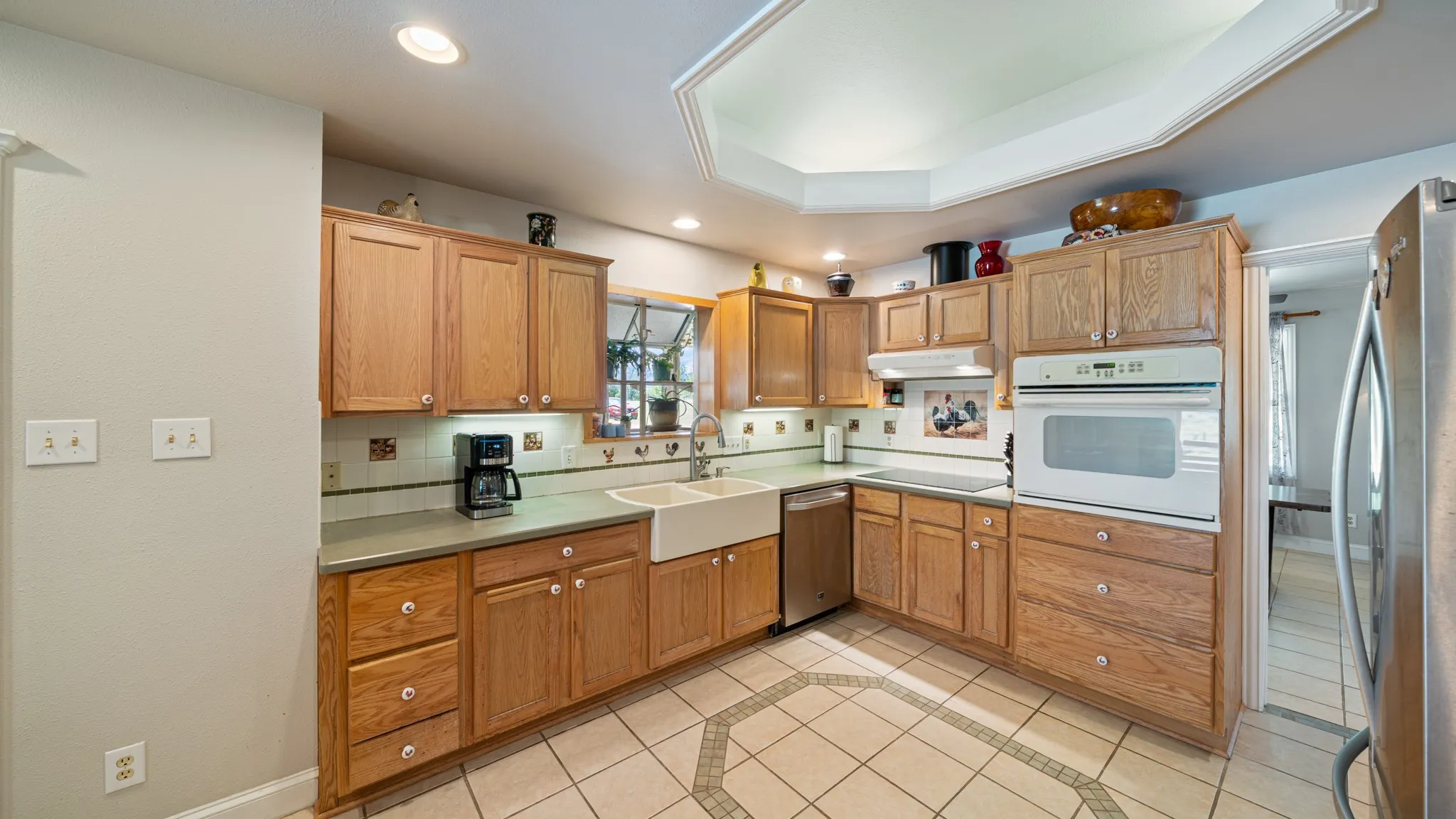 Kitchen featuring wood-finish cabinetry, tile flooring, recessed lighting, double basin farmhouse sink, and stainless steel appliances