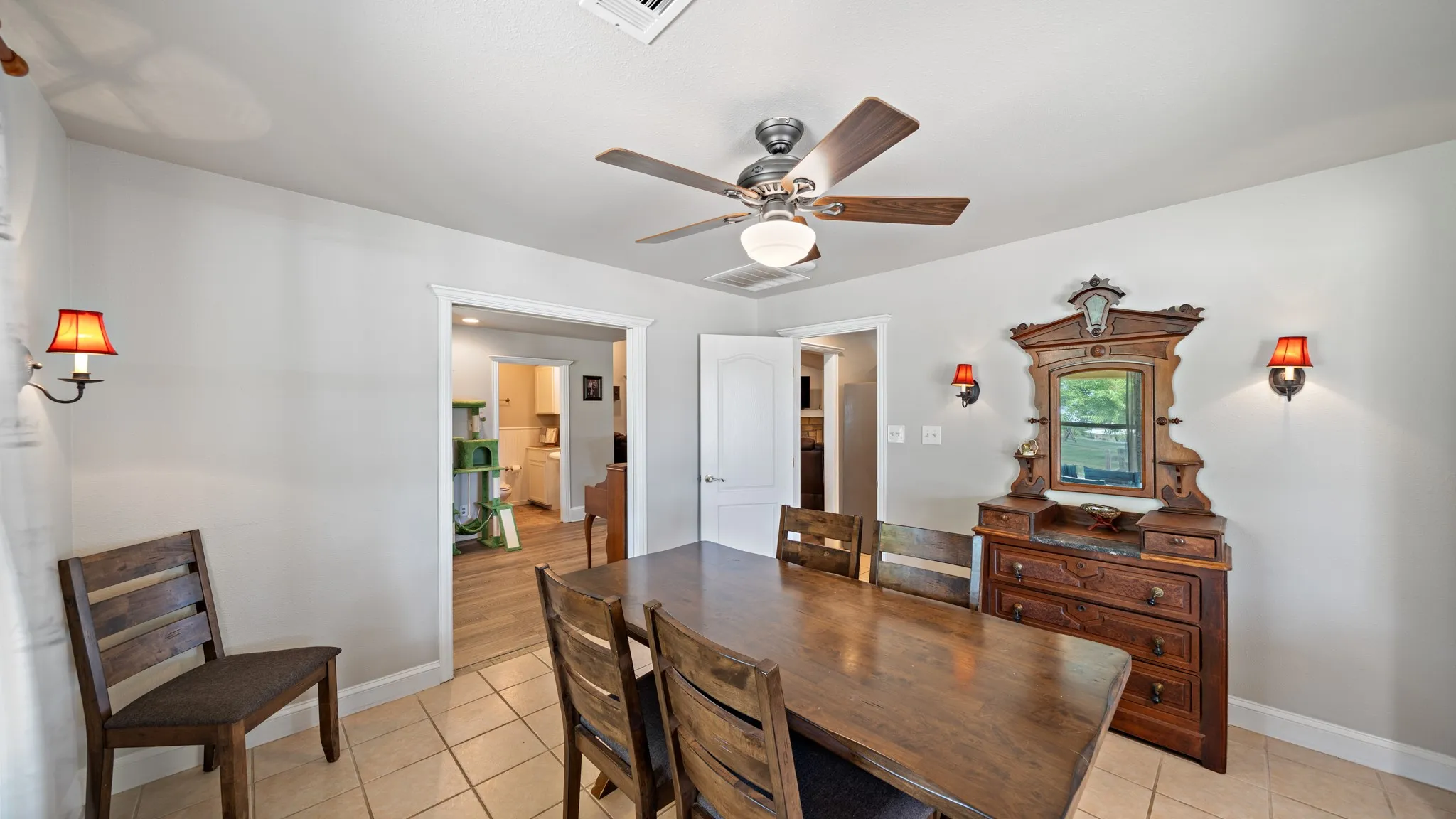 Spacious dining room with wood-finish flooring, ceiling fan with integrated lighting, and rich wood cabinetry