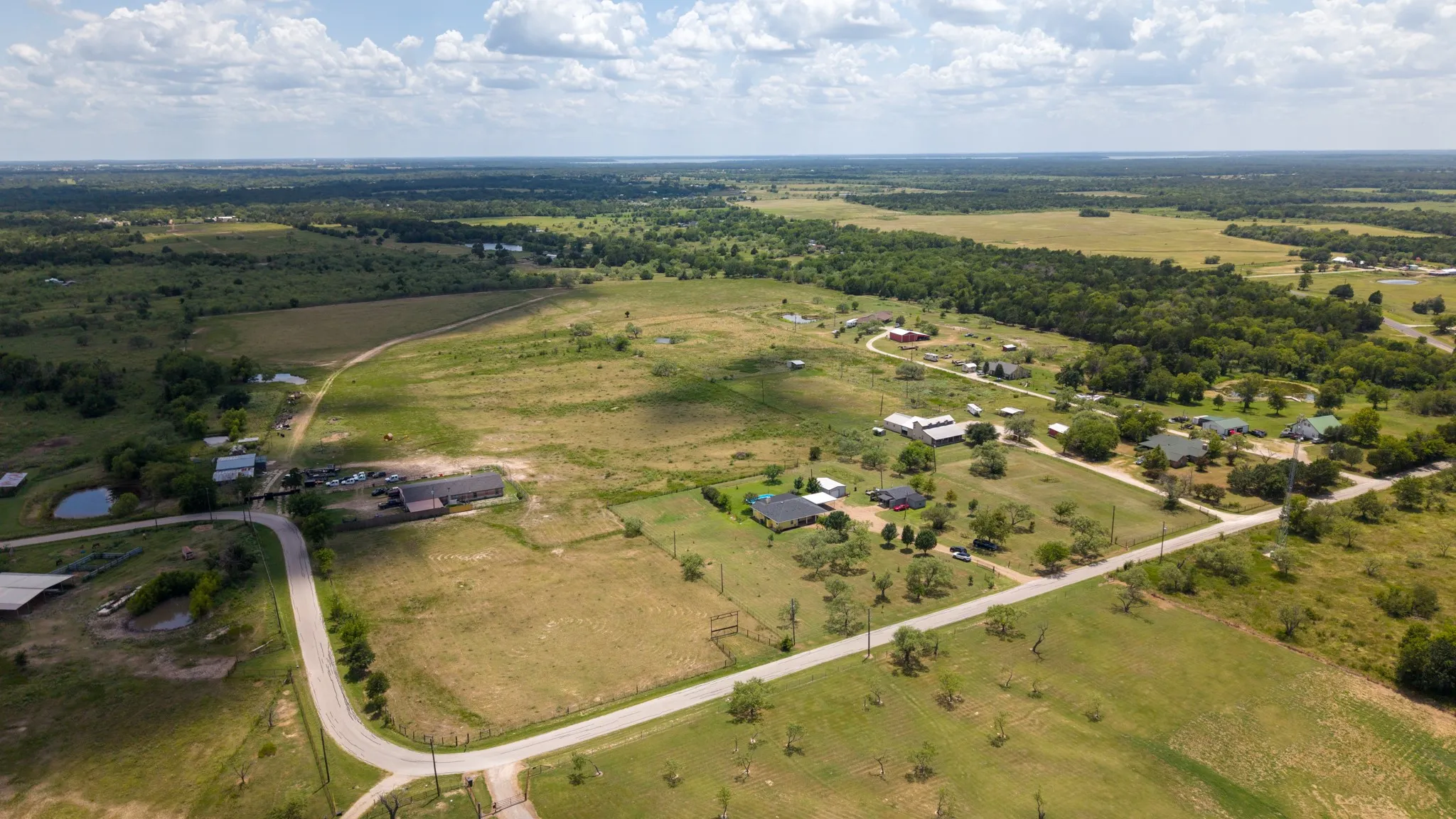 Expansive rural acreage featuring multiple residential structures, mature tree plantings throughout, and a network of paved driveways