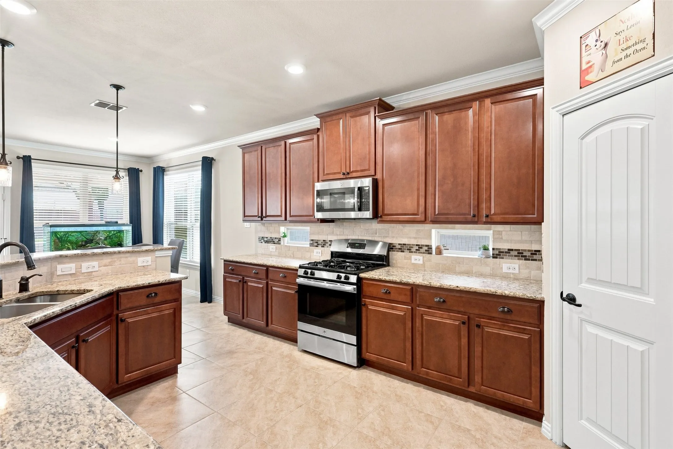 Open Gourmet kitchen featuring Gas Range and Oven, Walk-in Pantry, Decorative Windows, Ceramic Tile, and Breakfast Bar.