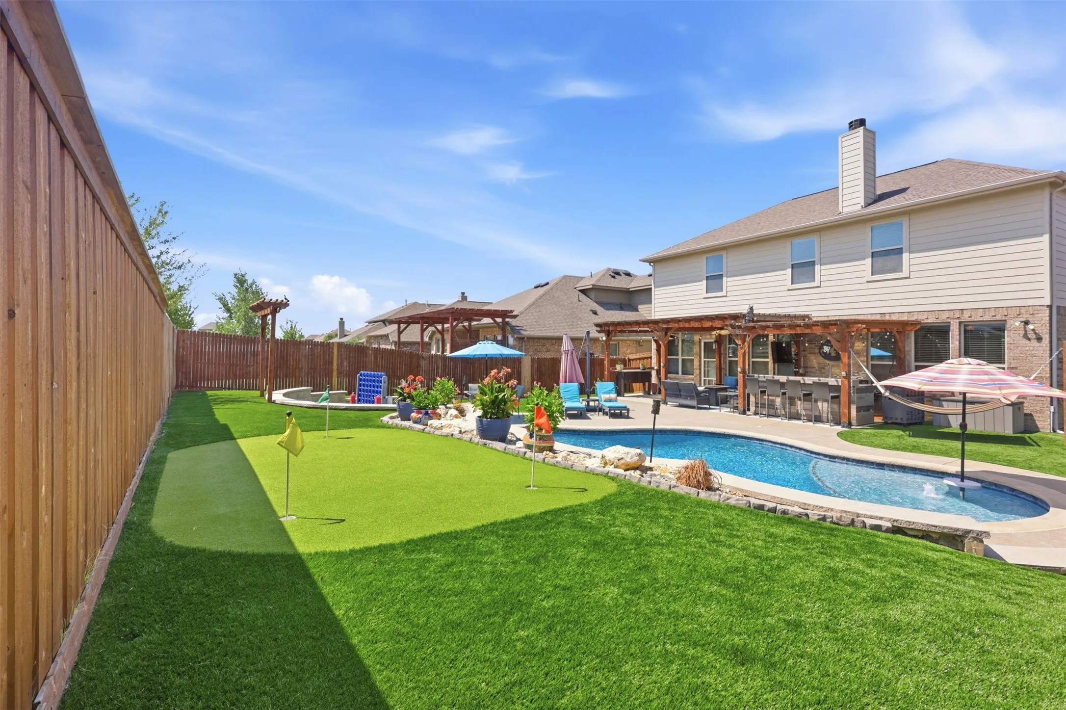 Resort-style Backyard with Mini-Golf Course, Smaller Pergola, Landscaping over Pool, and Commercial Grade Turf with Sprinklers and Drainage Systeim.