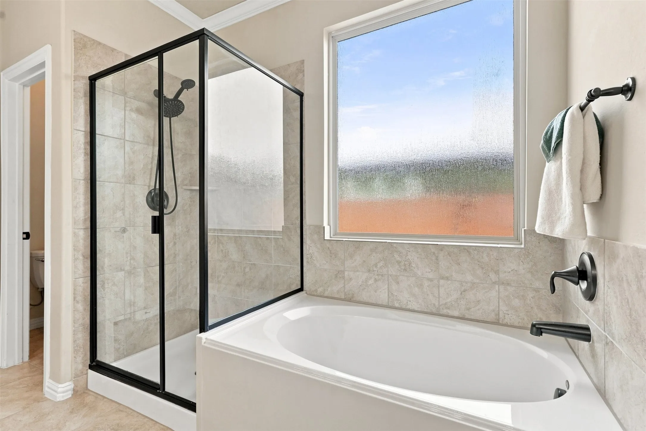 Separate Shower, Garden Tub with Window above and Tile Surround.