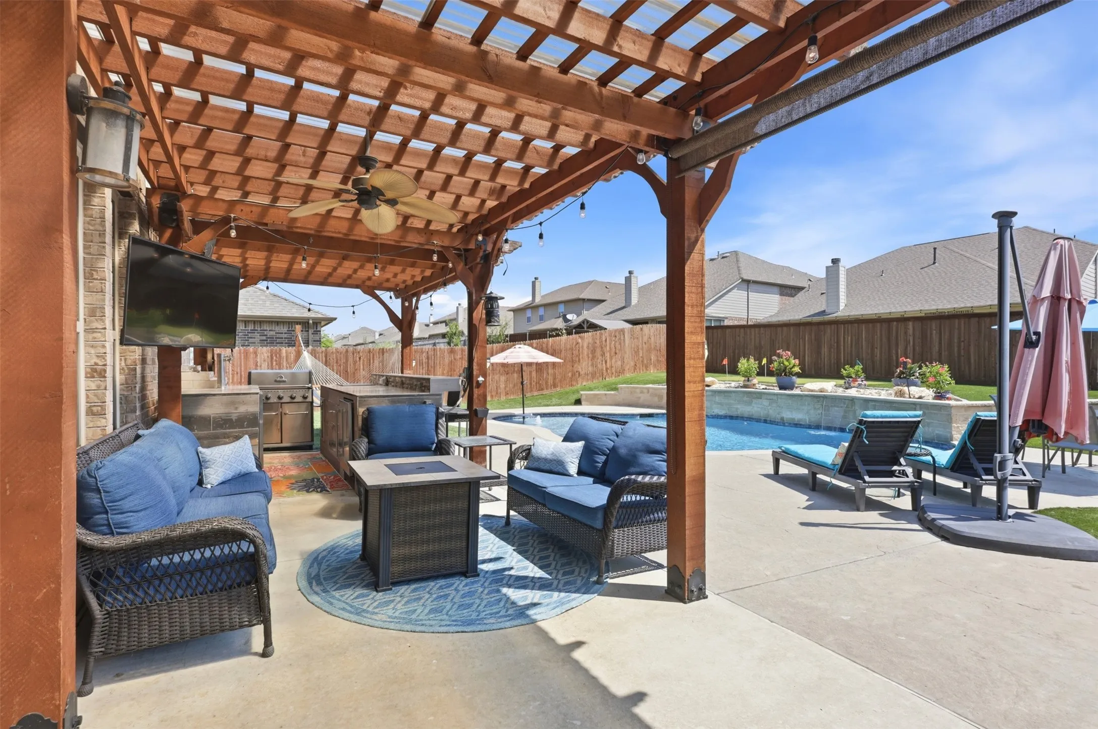 Outdoor Retreat featuring Pergola with Electricity and Fan, Mounted T.V., Fully Appointed Kitchen with Grill, Refrigerator, Kegerator, and Bar.