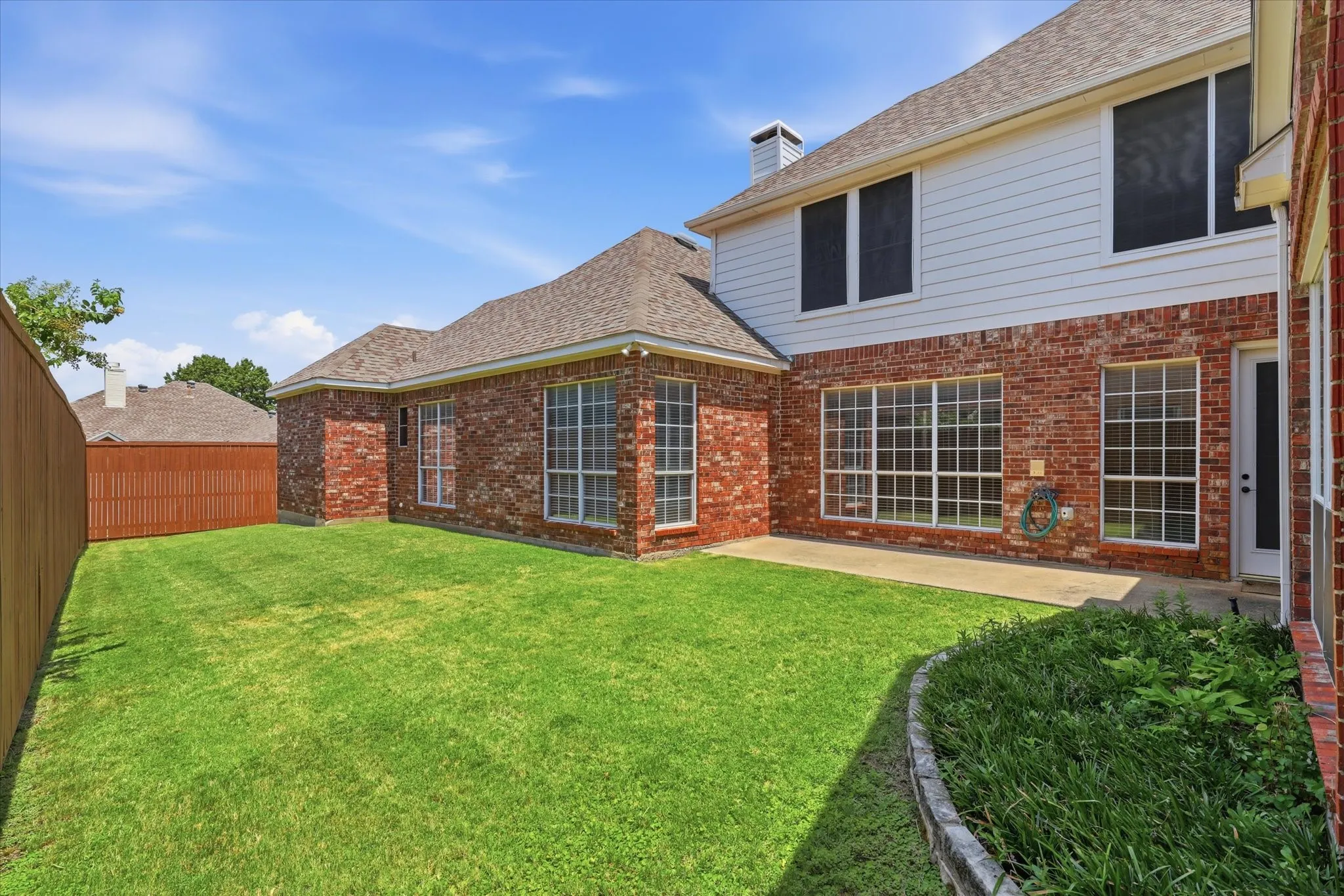 Rear elevation showcasing the home's attractive brick exterior and spacious backyard.  *Solar shades for these lower windows are stored inside the garage.
