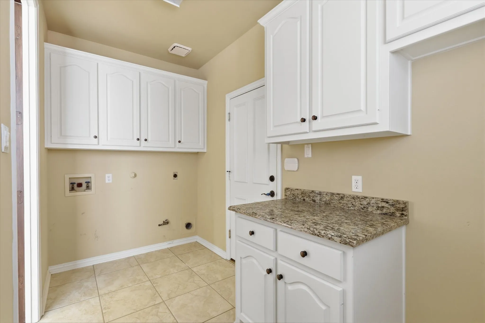 Functional laundry room with cabinetry and workspace for everyday convenience.  Room for Washer/Dryer and extra Refrigerator.