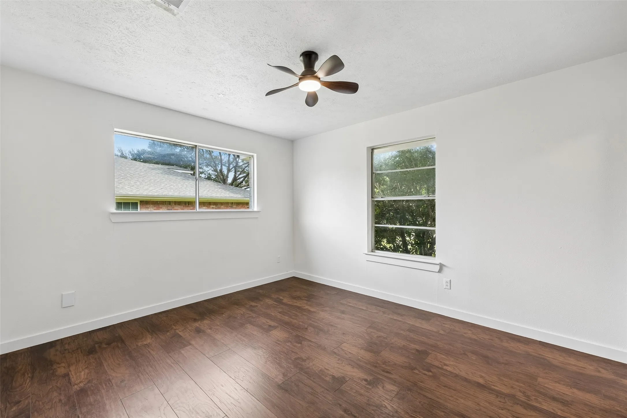 Laminate wood flooring, white painted walls, and a ceiling fan