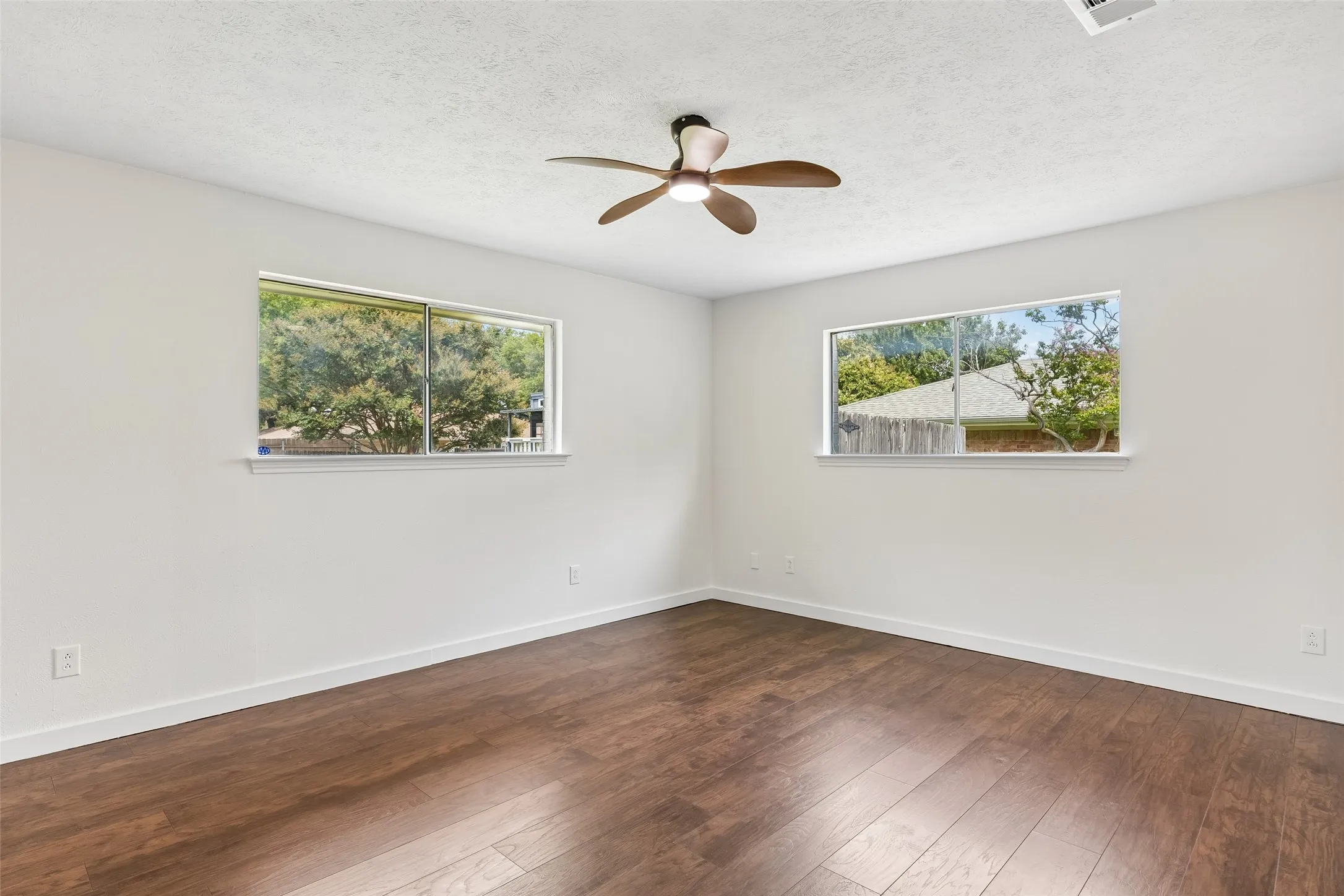 Laminate wood flooring, freshly painted walls, and a ceiling fan