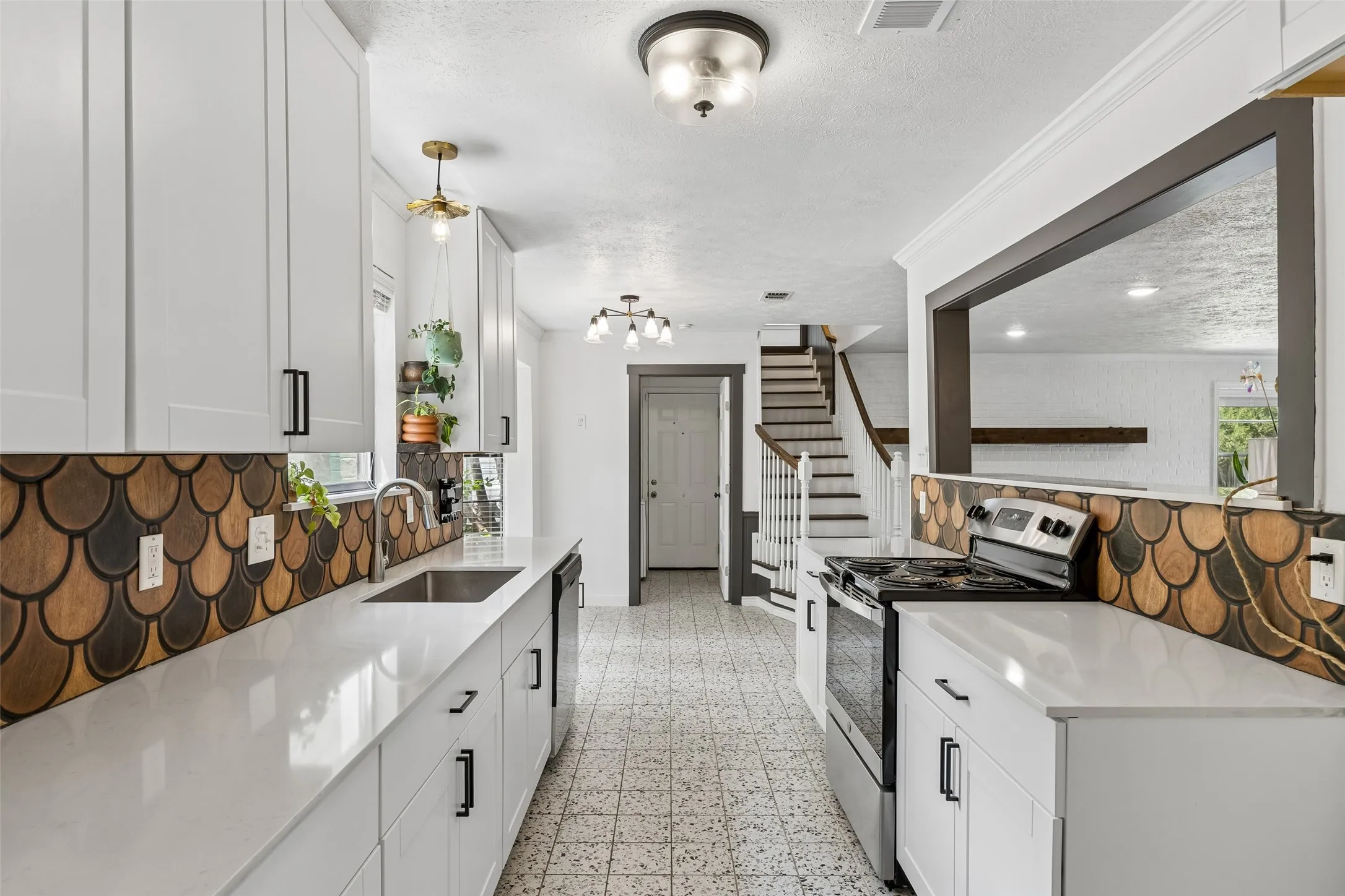 White 36" cabinetry,quartz countertops, a unique scallop-patterned backsplash, and stainless steel appliances