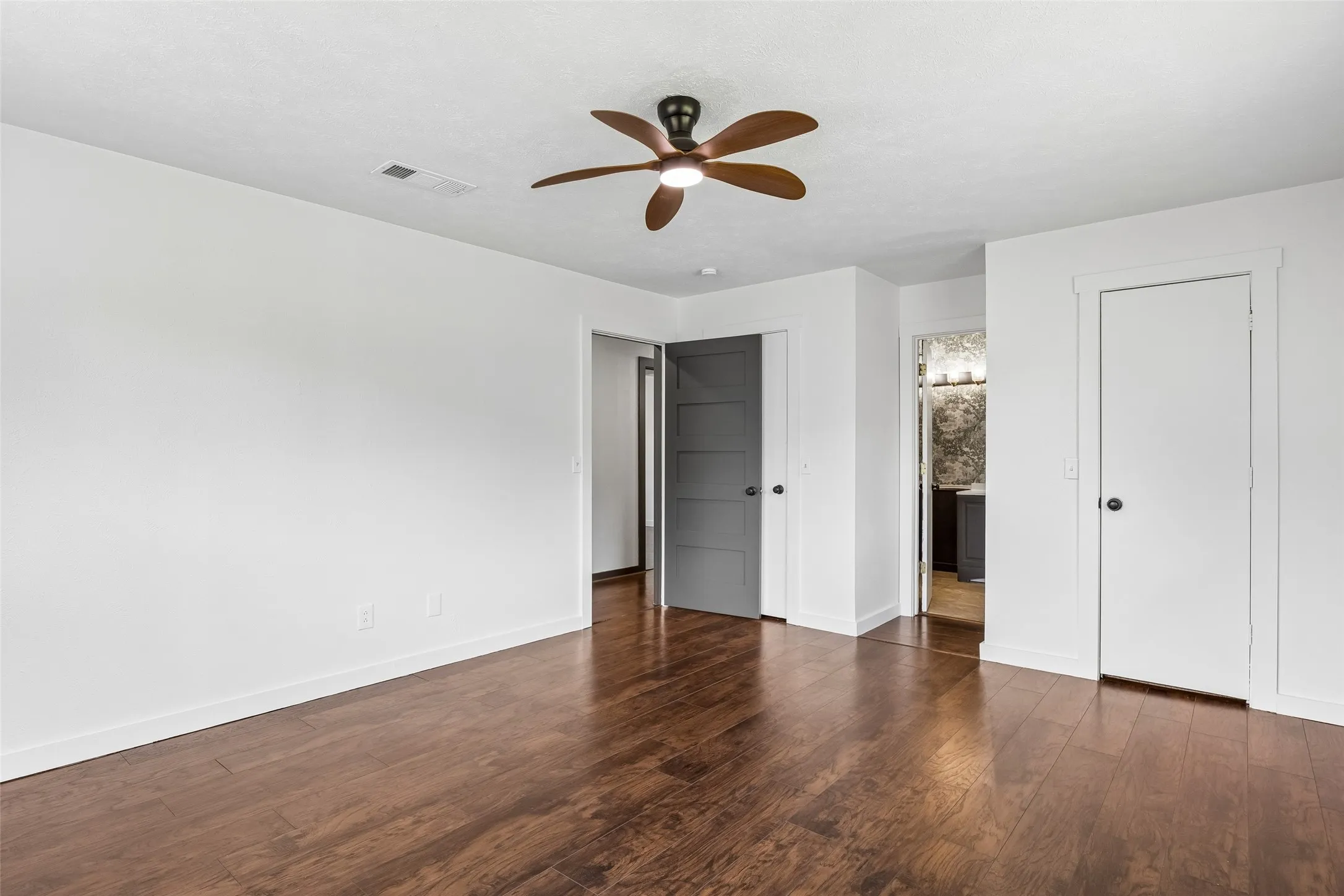 Laminate wood flooring, white walls, ceiling fan, and white trim