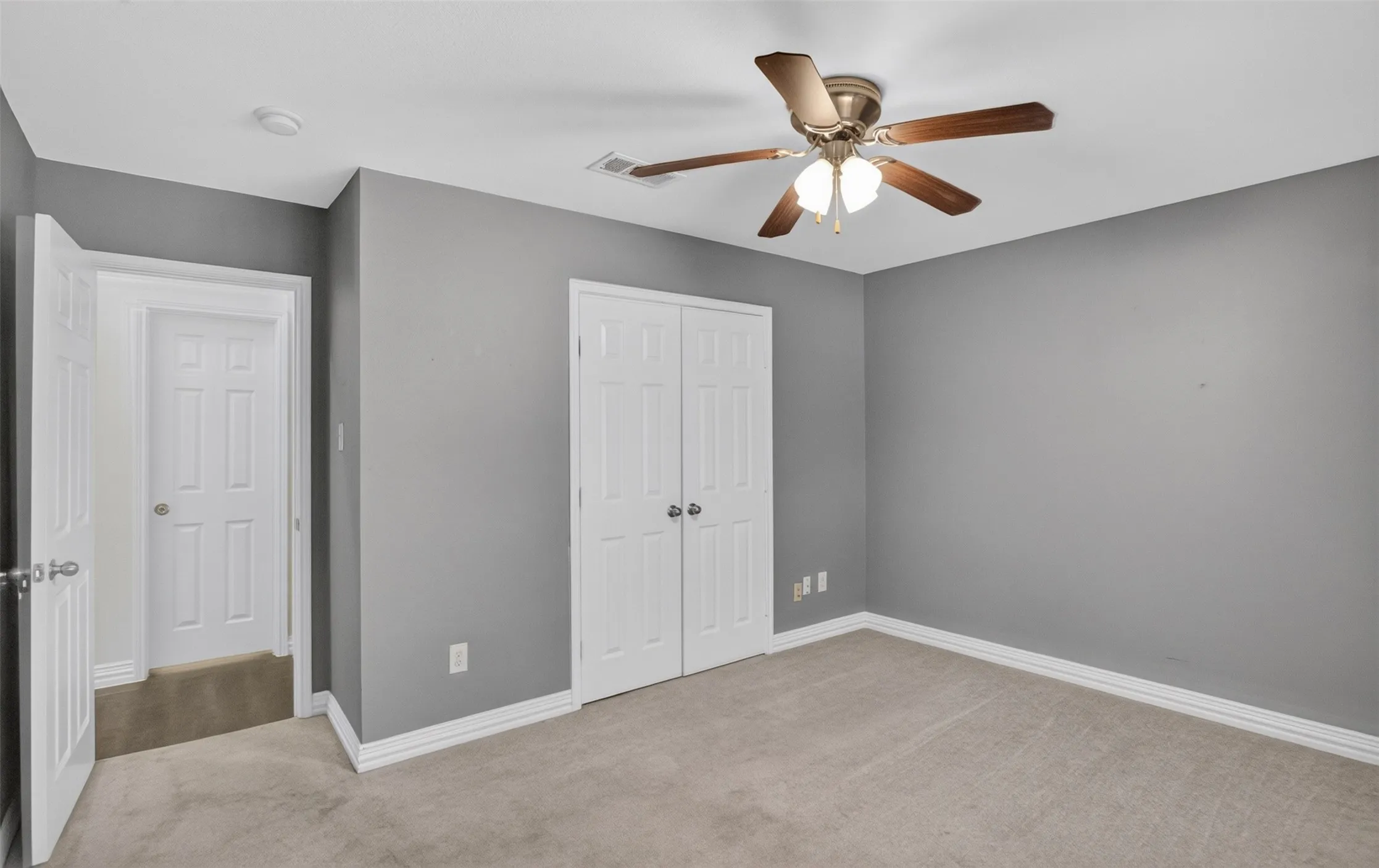 Spacious bedroom with neutral gray walls, neutral carpet flooring, and abundant natural light