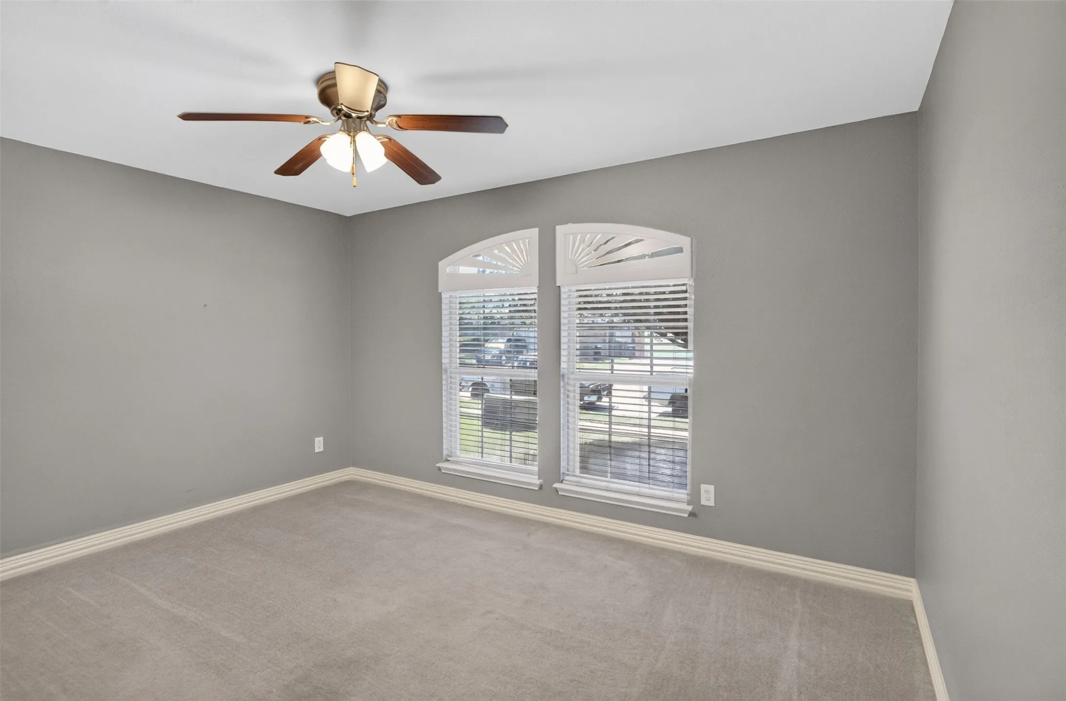 Room featuring light gray wall paint, light-colored carpet flooring, white baseboards, and a ceiling fan with integrated lighting