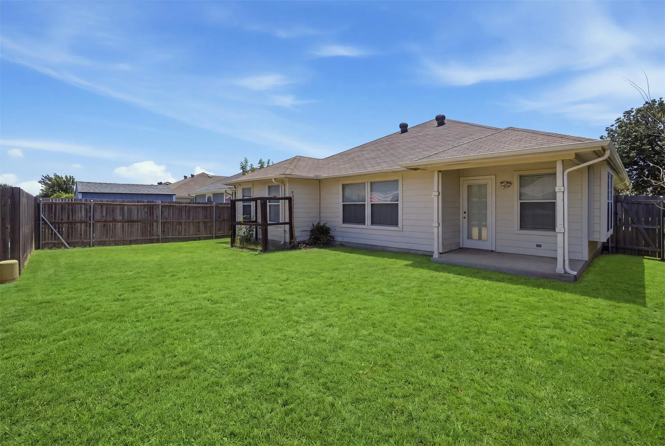 Spacious backyard featuring a covered patio with concrete flooring, siding exterior, shingle roofing, and a privacy fence