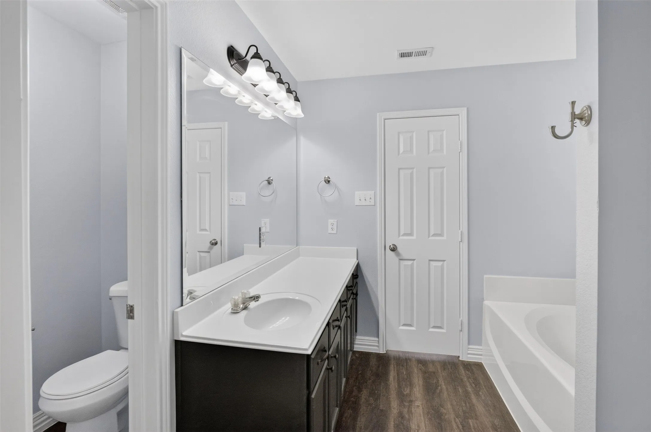 Contemporary bathroom featuring a dark wood-finish vanity with a white countertop and integrated sink