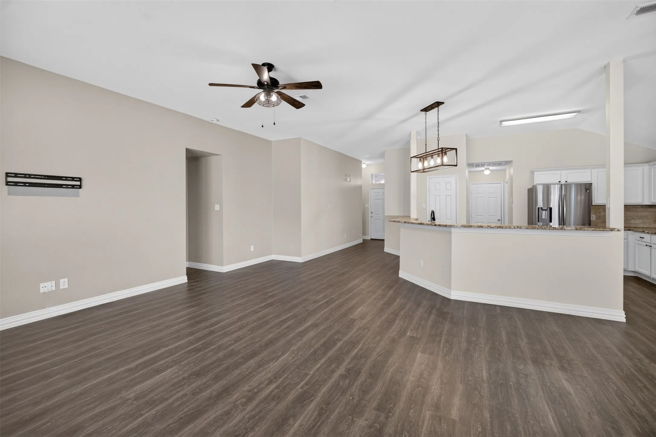 Expansive room featuring wood-finish flooring, vaulted ceilings, and a ceiling fan