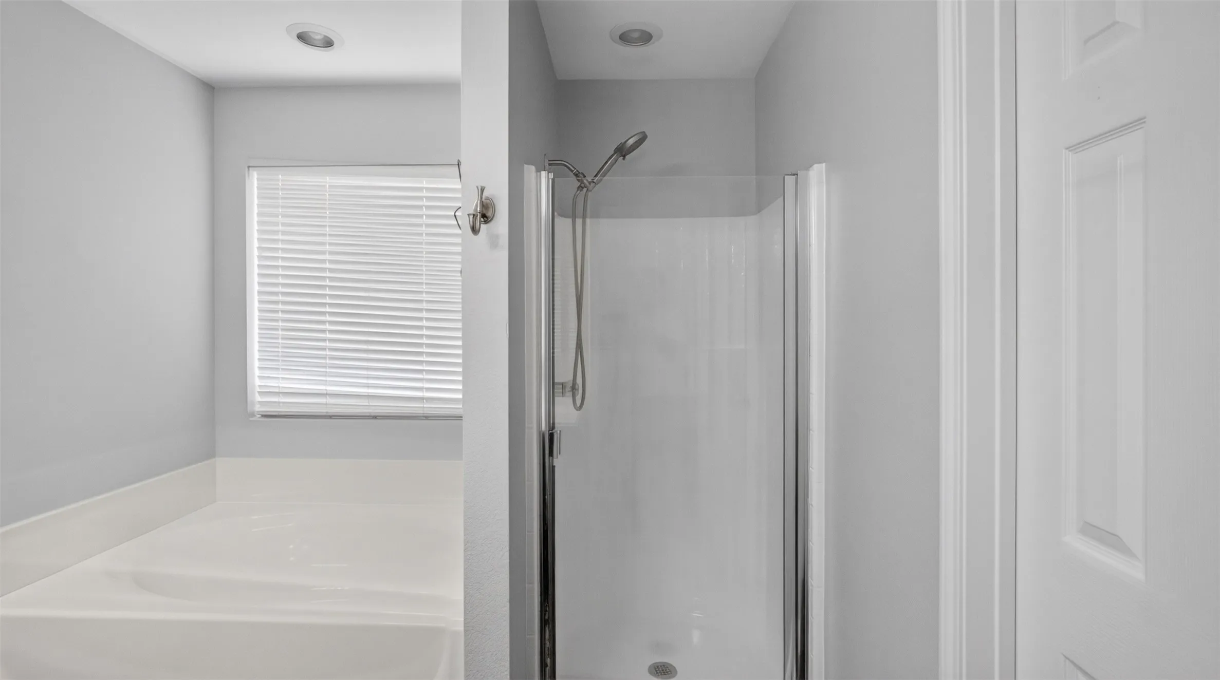 Bathroom featuring a white bathtub, enclosed shower with chrome fixtures, a window with horizontal blinds, and recessed lighting