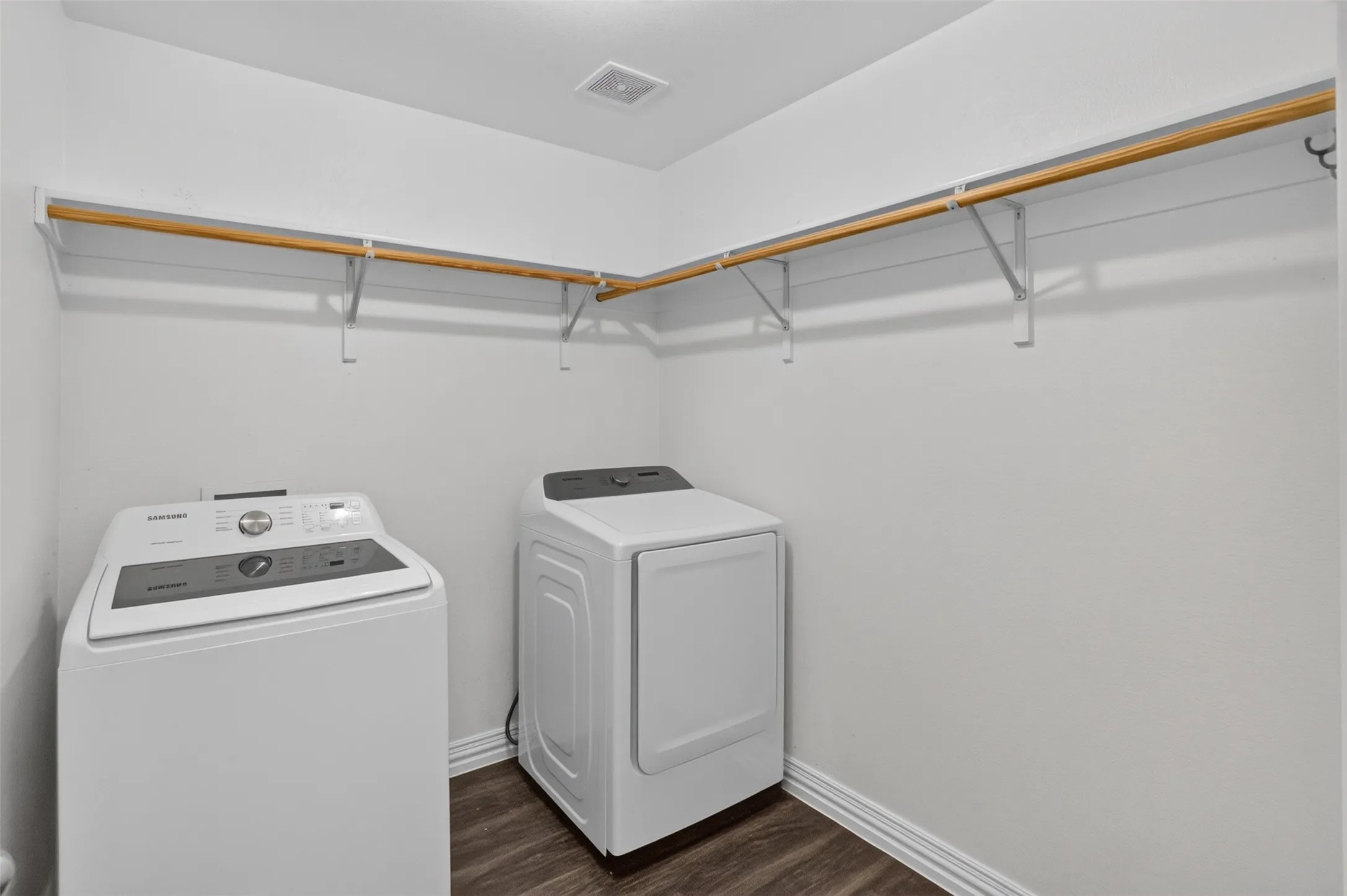 Dedicated laundry room featuring side-by-side washer and dryer appliances, wood-finish shelving with metal brackets for additional storage, wood-finish flooring, and recessed ceiling lighting