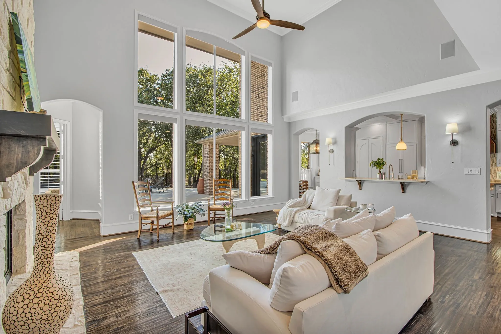 Bright and airy living room showcasing soaring ceilings, a wall of multi-pane windows flooding the space with natural light, and hardwood flooring throughout.