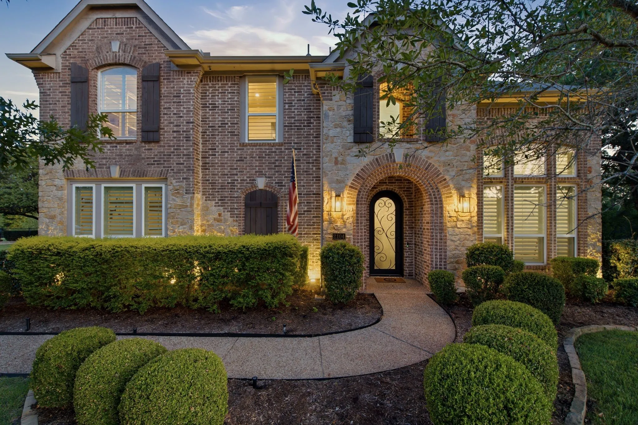 Brick and stone exterior featuring an arched entryway with an ornate iron door.